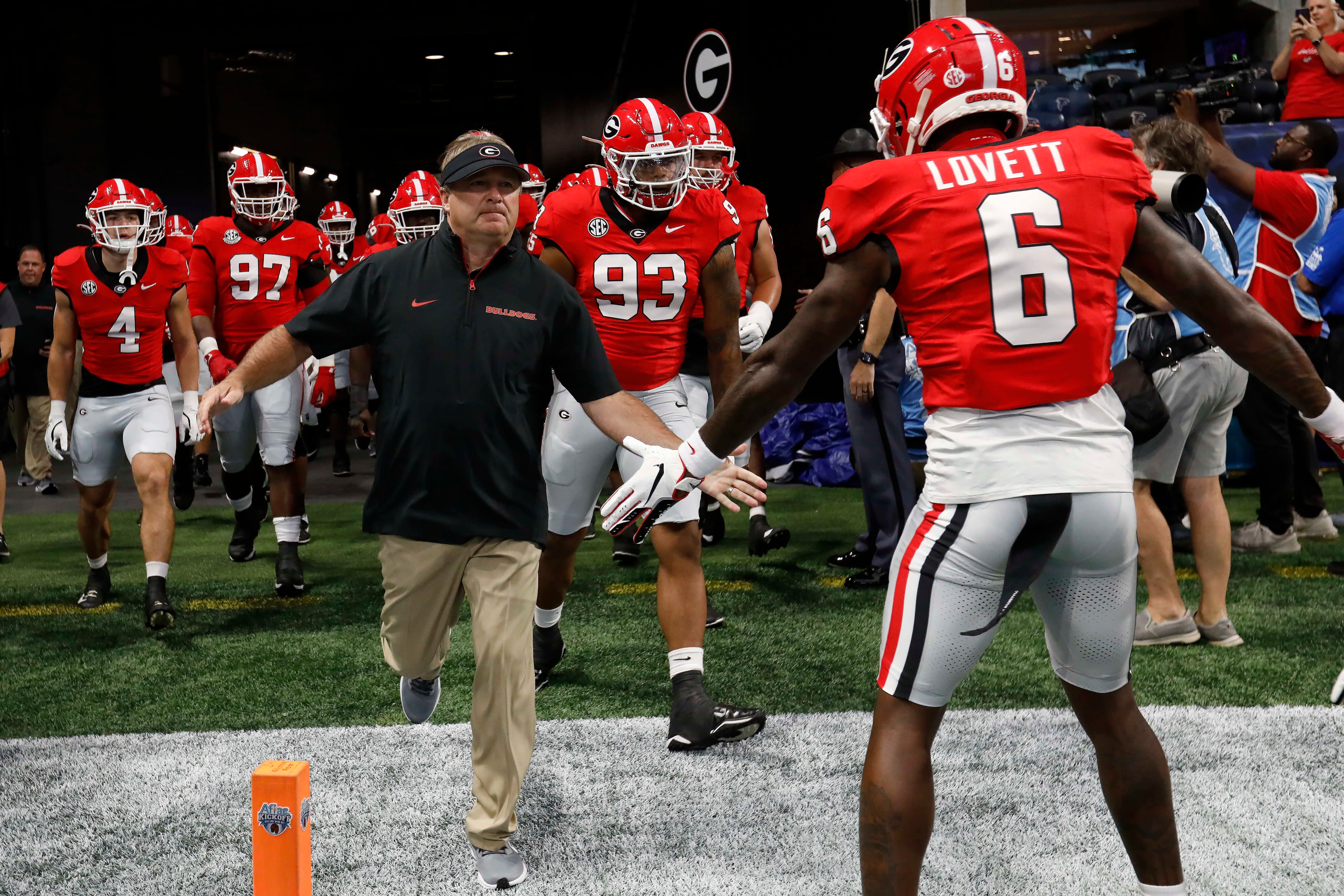 Kirby Smart runs out on to the field with his players for Georgia Bulldogs Football