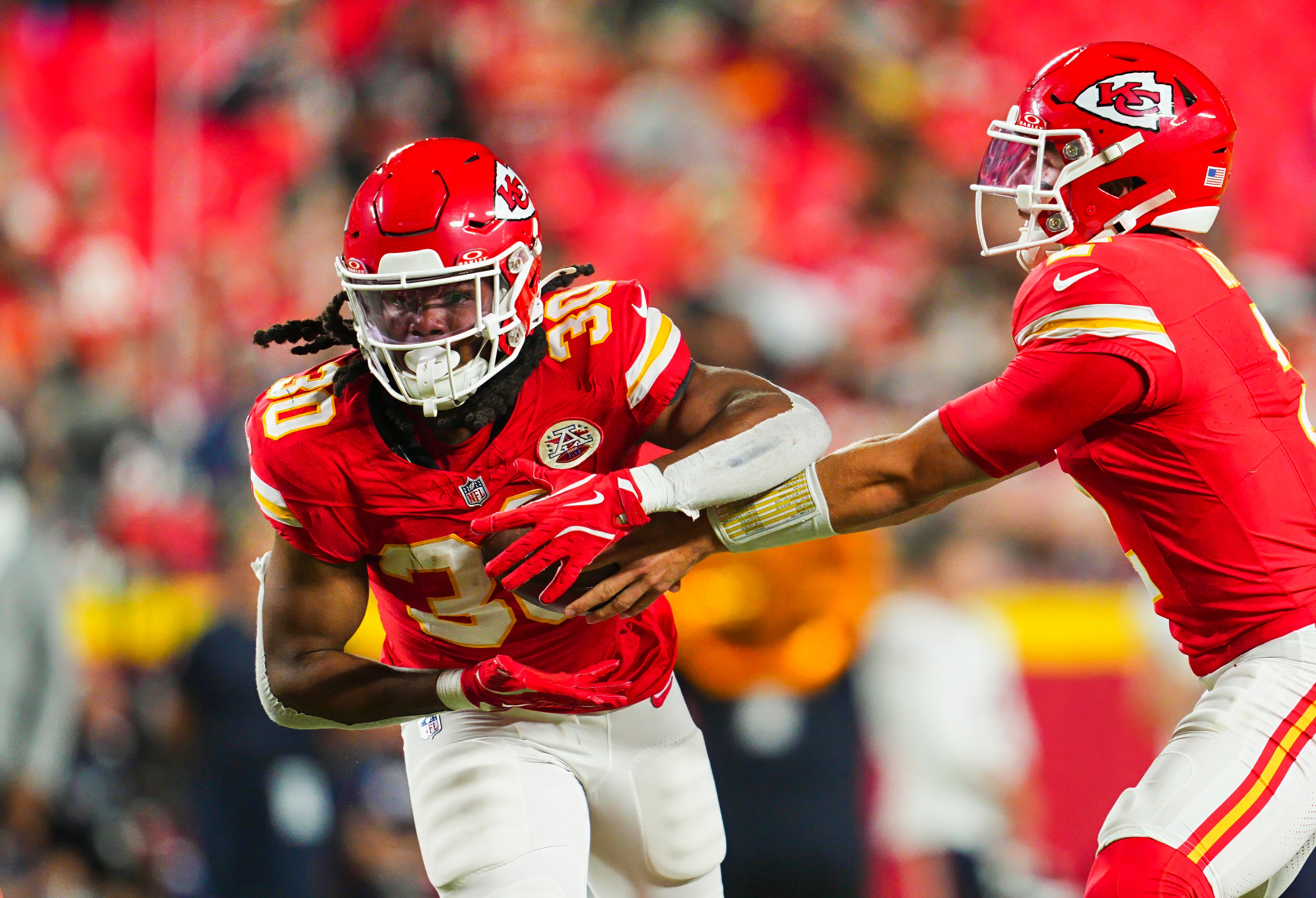 Aug 22, 2024; Kansas City, Missouri, USA; Kansas City Chiefs running back Keaontay Ingram (30) takes the handoff from quarterback Bailey Zappe (2) during the second half against the Chicago Bears at GEHA Field at Arrowhead Stadium.