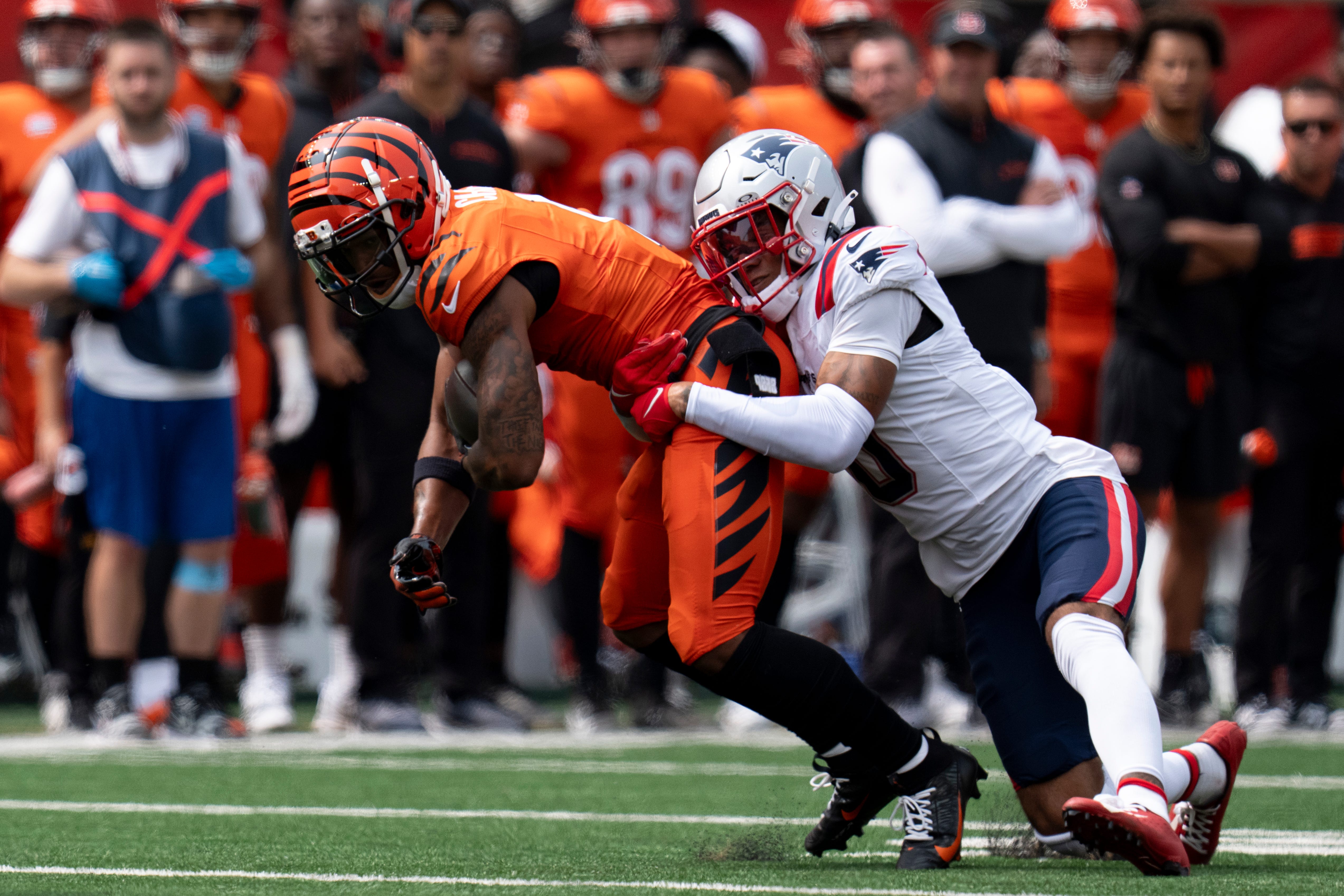 Cincinnati Bengals wide receiver Ja'Marr Chase (1) is tackled by New England Patriots corner back Christian Gonzalez (0) in the second quarter of the NFL game at Paycor Stadium in Cincinnati on Sunday, Sept. 8, 2024.