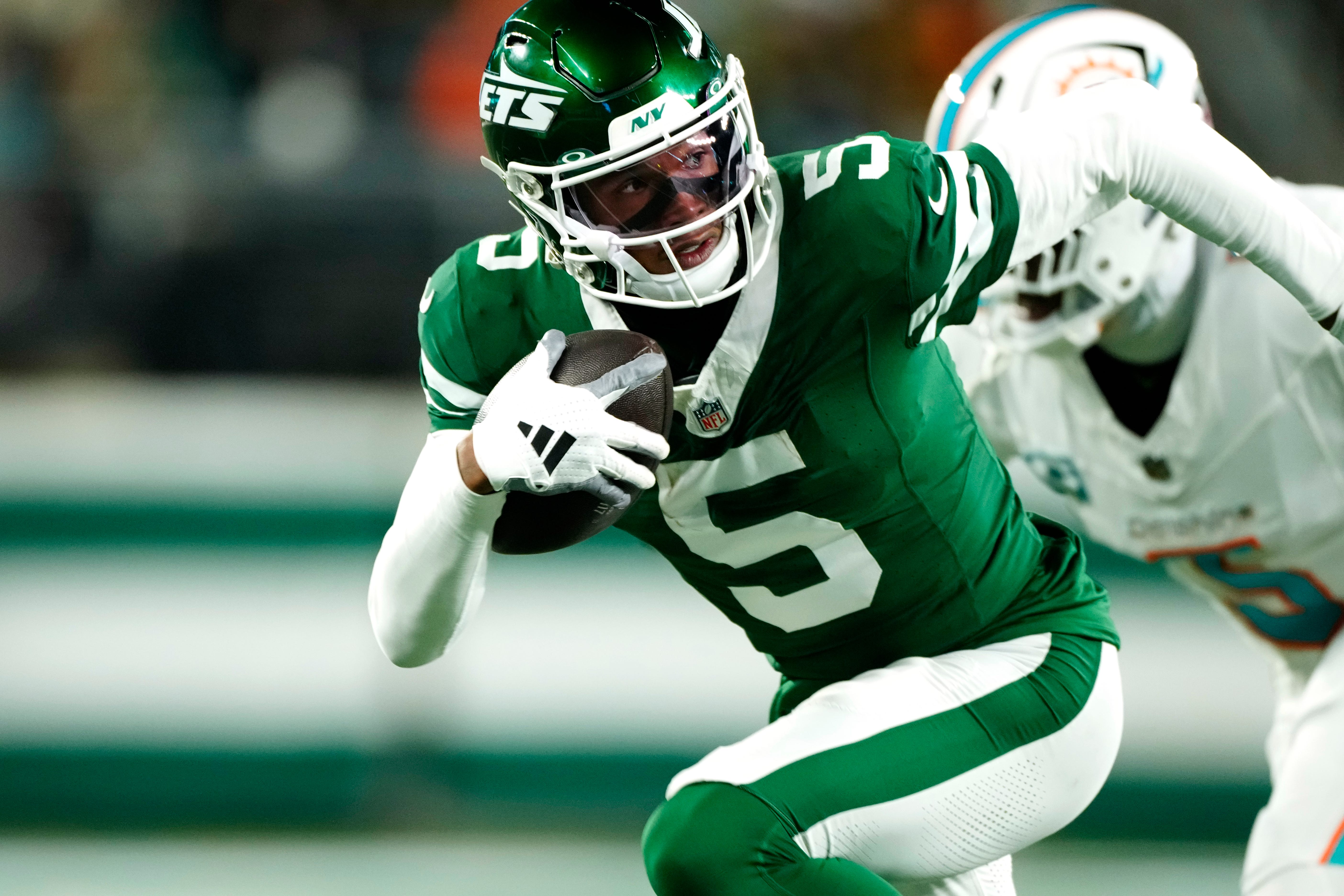 New York Jets wide receiver Garrett Wilson (5) runs with the ball past Miami Dolphins cornerback Jalen Ramsey (5), Sunday January 5, 2025, in East Rutherford.