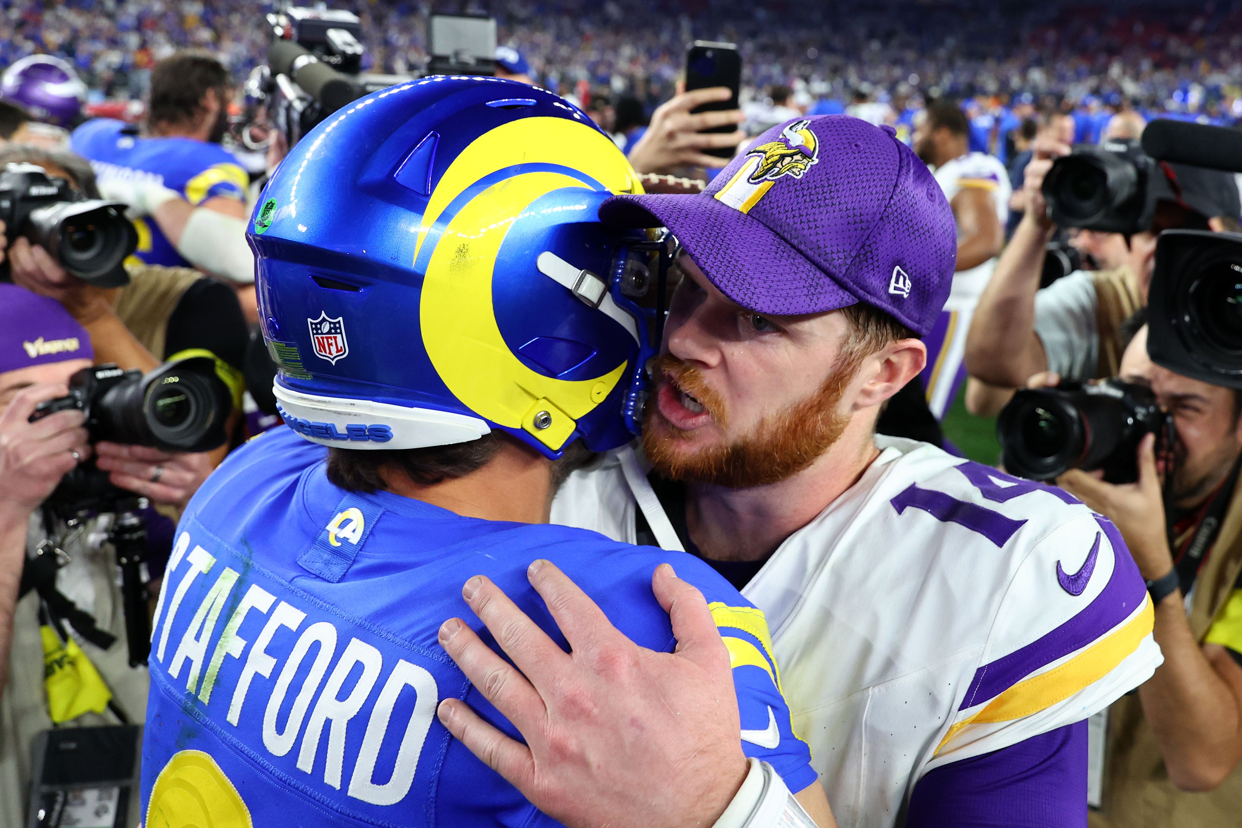 Jan 13, 2025; Glendale, AZ, USA; Minnesota Vikings quarterback Sam Darnold (14) and Los Angeles Rams quarterback Matthew Stafford (9) hug after the NFC wild card game at State Farm Stadium.