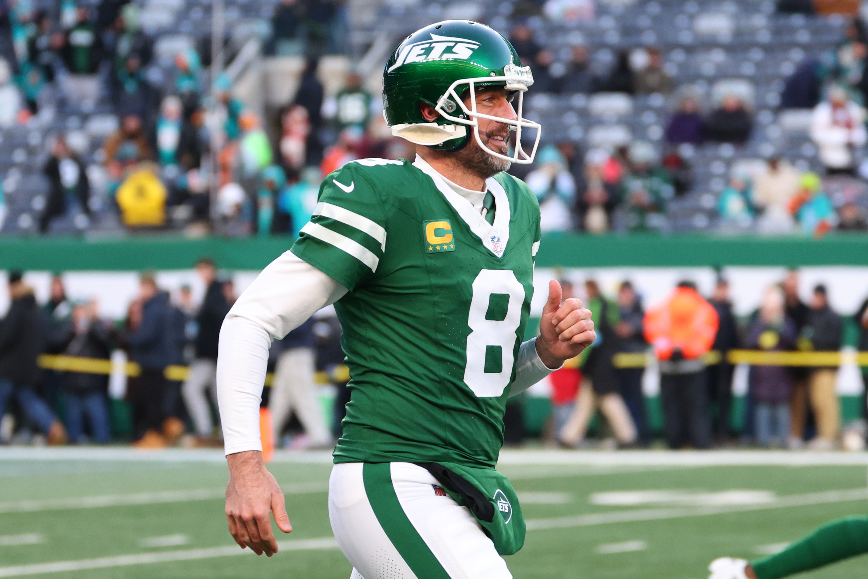 Jan 5, 2025; East Rutherford, New Jersey, USA; New York Jets quarterback Aaron Rodgers (8) runs onto the field for pregame warmups for their game against the Miami Dolphins at MetLife Stadium. Mandatory Credit: Ed Mulholland-Imagn Images