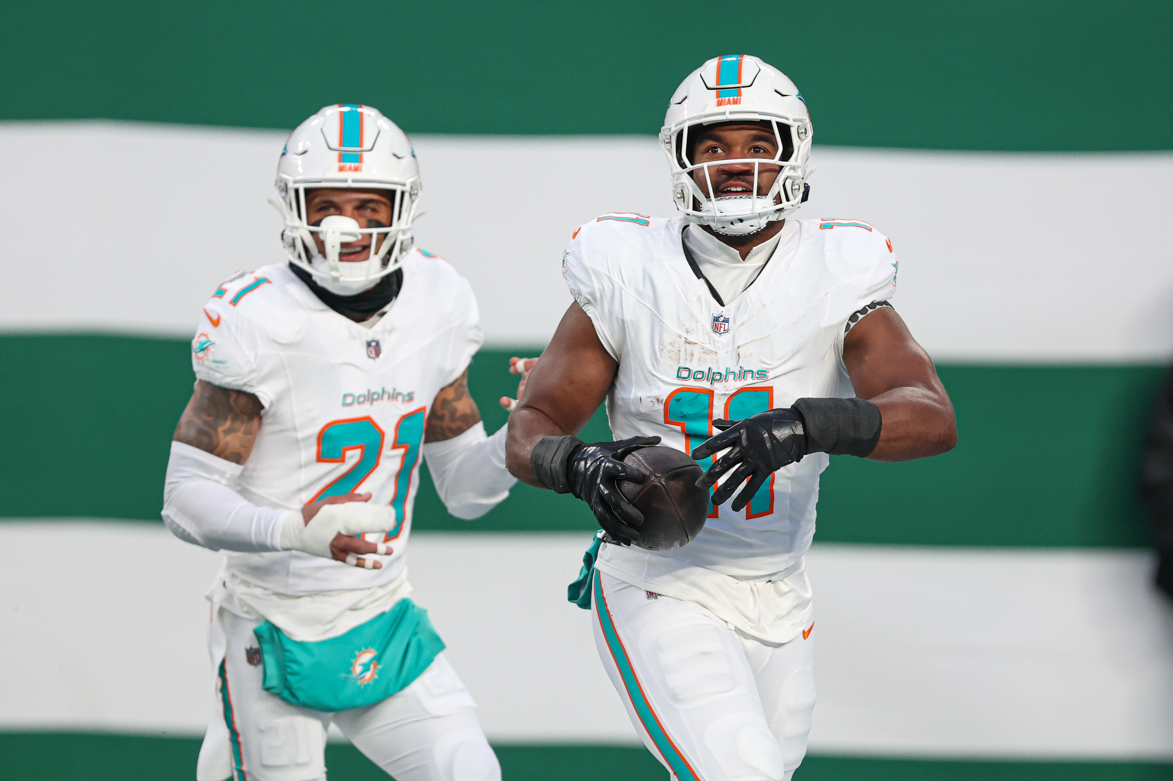 Jan 5, 2025; East Rutherford, New Jersey, USA; Miami Dolphins linebacker Tyrel Dodson (11) celebrates his interception with safety Jordan Poyer (21) during the first quarter against the New York Jets at MetLife Stadium.