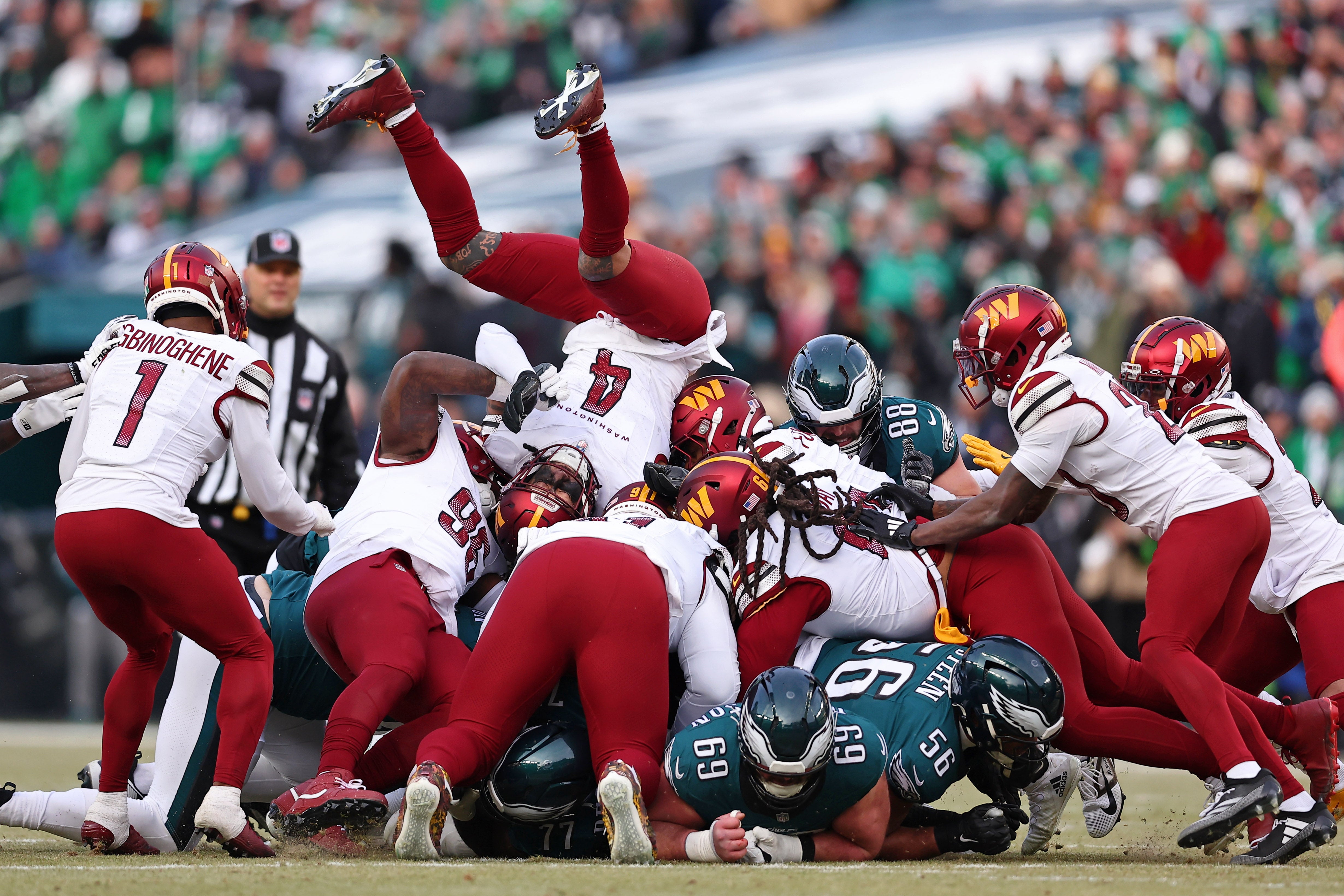 Washington Commanders linebacker Frankie Luvu (4) is upended on top of a pile after Philadelphia Eagles quarterback Jalen Hurts (not pictured) rushed for a first down during the first half in the NFC Championship