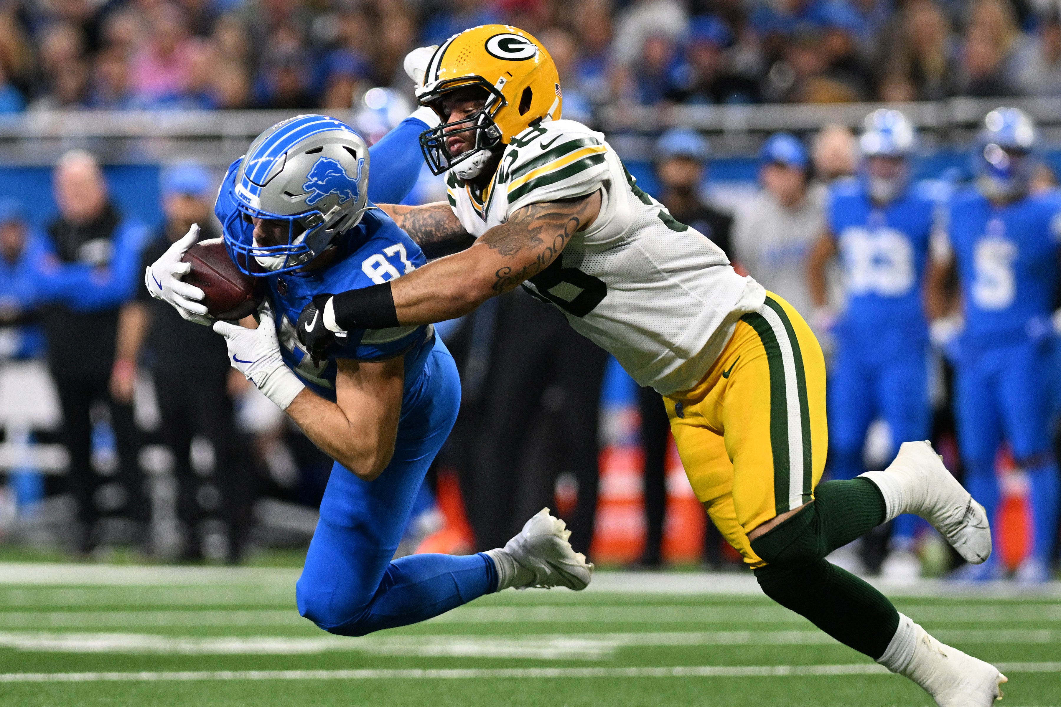 Detroit Lions tight end Sam LaPorta (87) makes a leaping catch in front of Green Bay Packers linebacker Isaiah McDuffie (58) in the fourth quarter at Ford Field