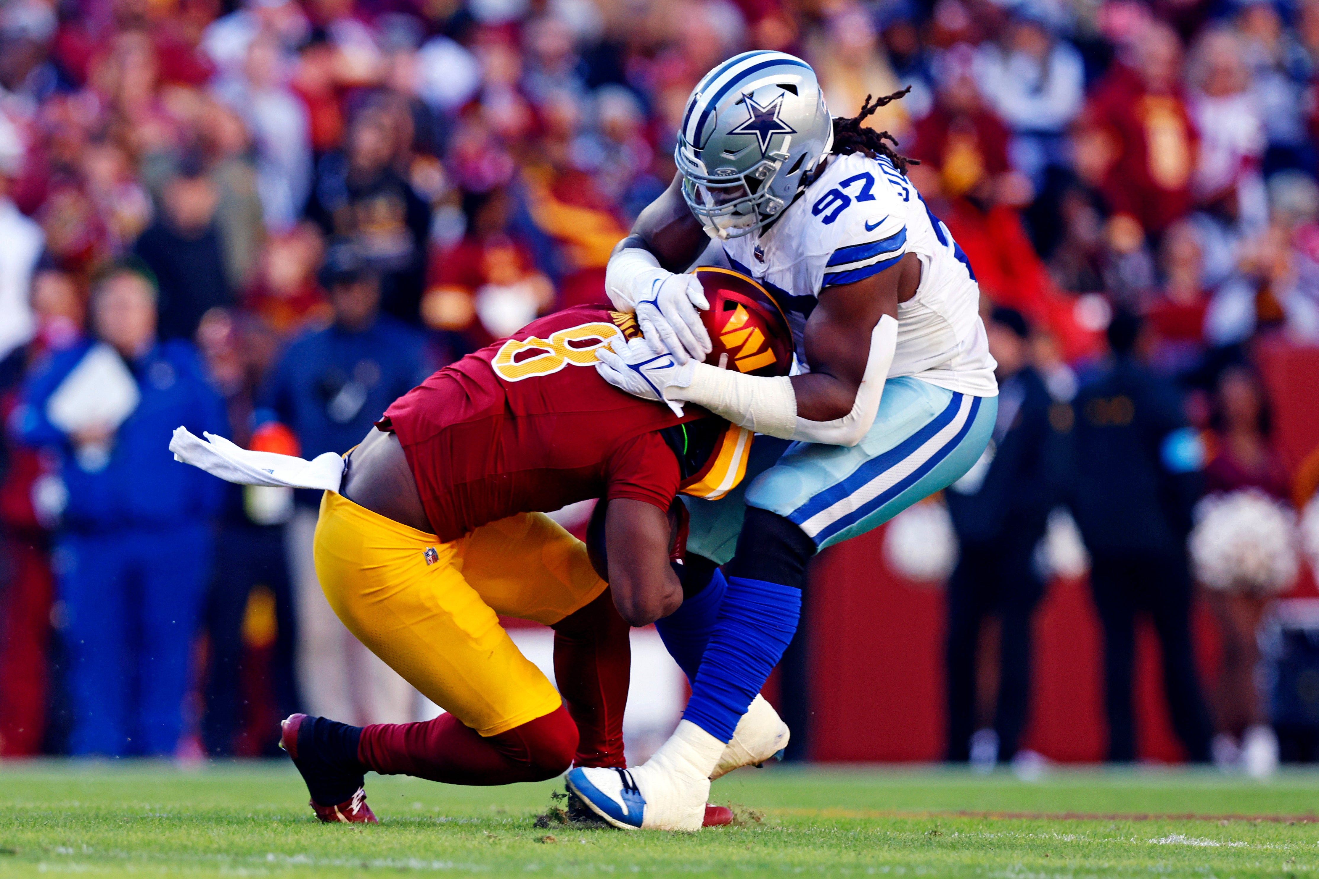 Washington Commanders running back Brian Robinson Jr. (8) is tackled by Dallas Cowboys defensive tackle Osa Odighizuwa (97) during the second quarter at Northwest Stadium.