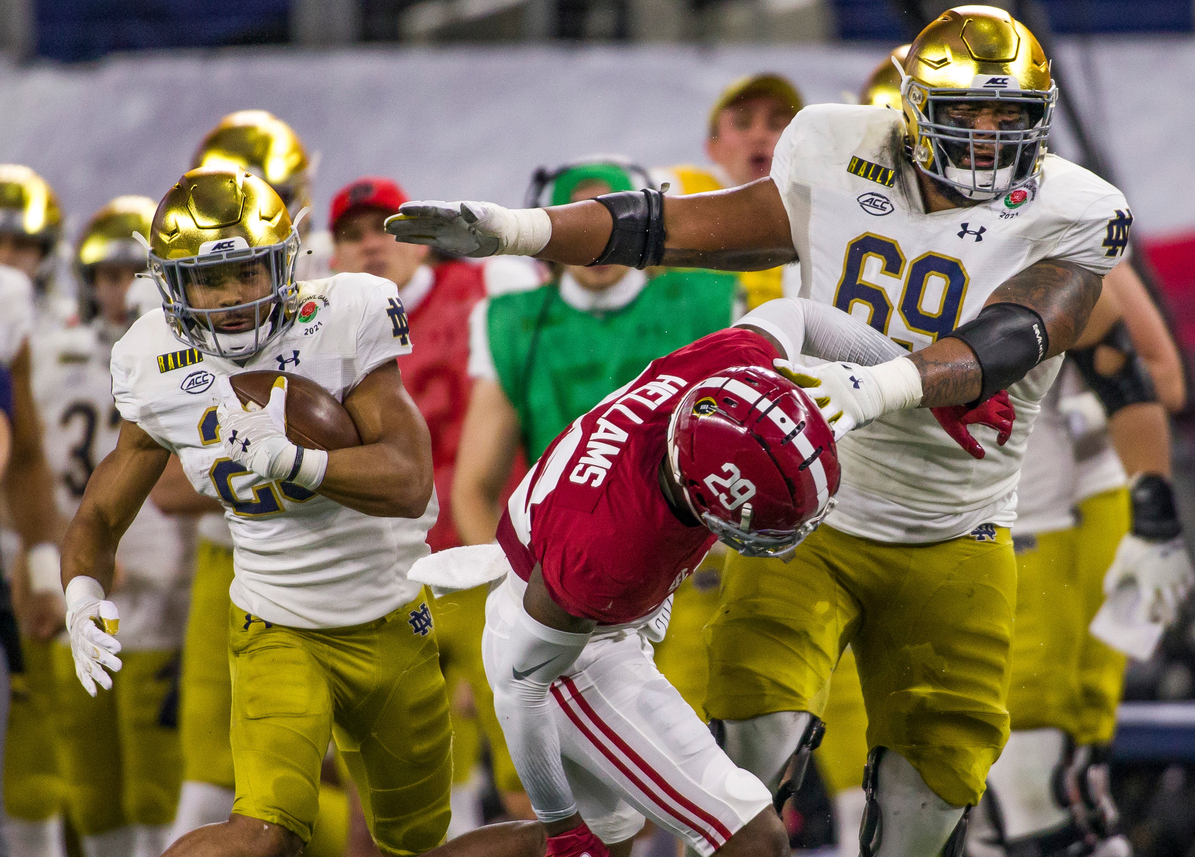 Notre Dame s Chris Tyree (25) runs the ball as teammate Aaron Banks (69) holds off Alabama s DeMarcco Hellams (29) during the 2021 College Football Playoff Rose Bowl game on Friday, Jan. 1, 2021, inside AT&T Stadium in Arlington, Texas.