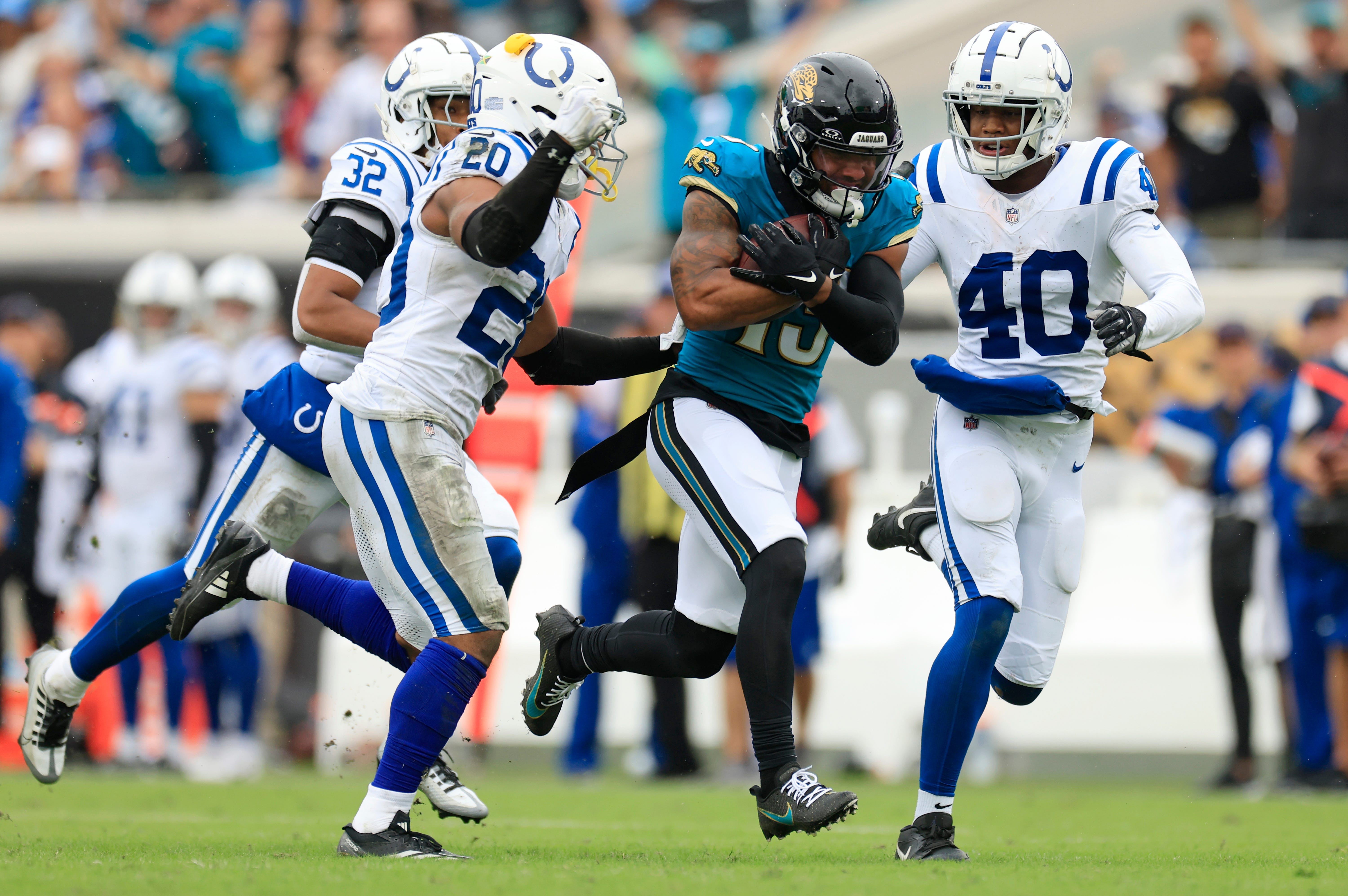 Jacksonville Jaguars wide receiver Christian Kirk (13) rushes for yards against Indianapolis Colts safety Nick Cross (20) and cornerback Jaylon Jones (40) during the fourth quarter of an NFL football matchup Sunday, Oct. 6, 2024 at EverBank Stadium in Jacksonville, Fla. The Jaguars edged the Colts on a field goal 37-34.