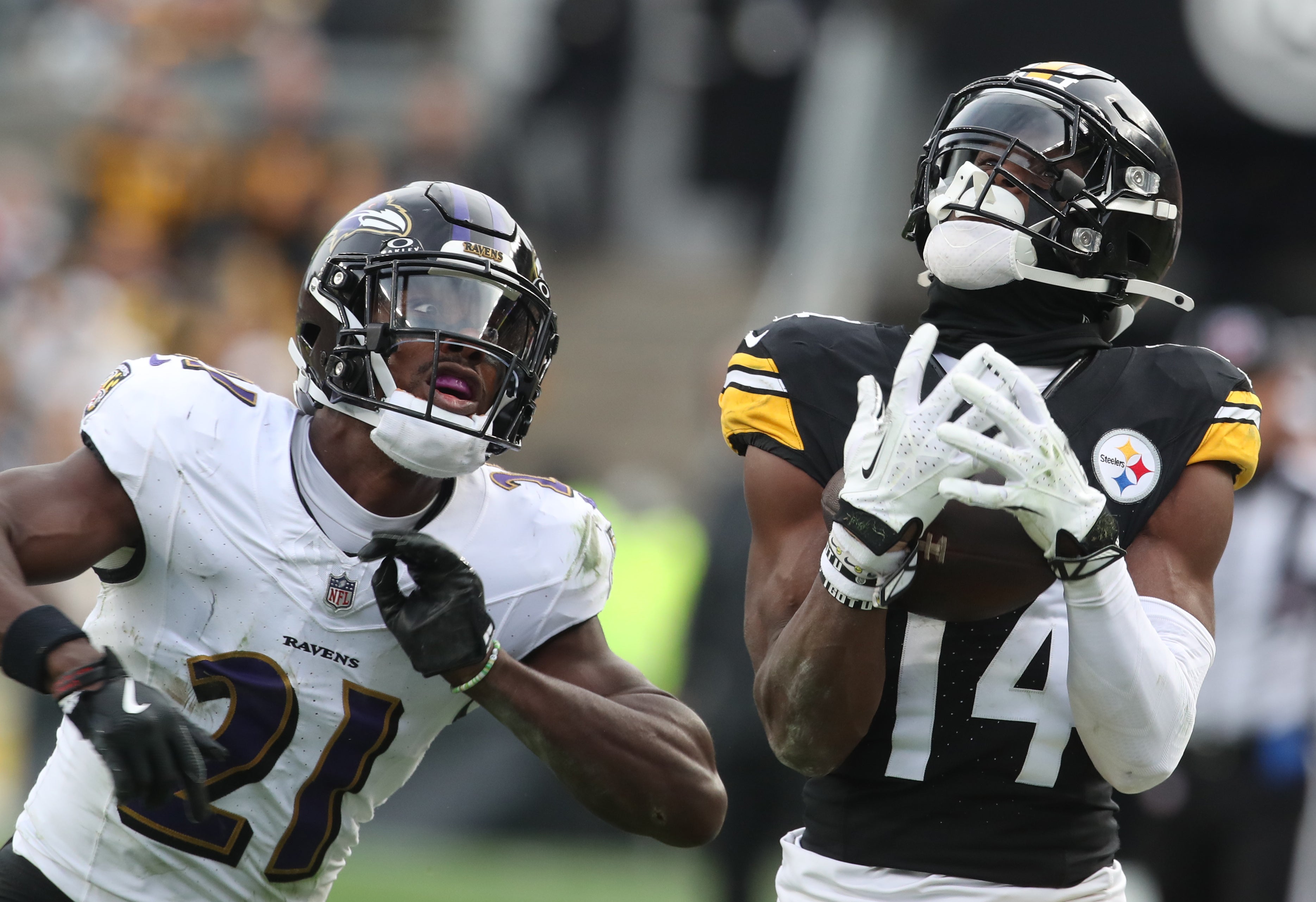 Pittsburgh Steelers wide receiver George Pickens (14) catches a pass behind Baltimore Ravens cornerback Brandon Stephens (21) during the third quarter at Acrisure Stadium.