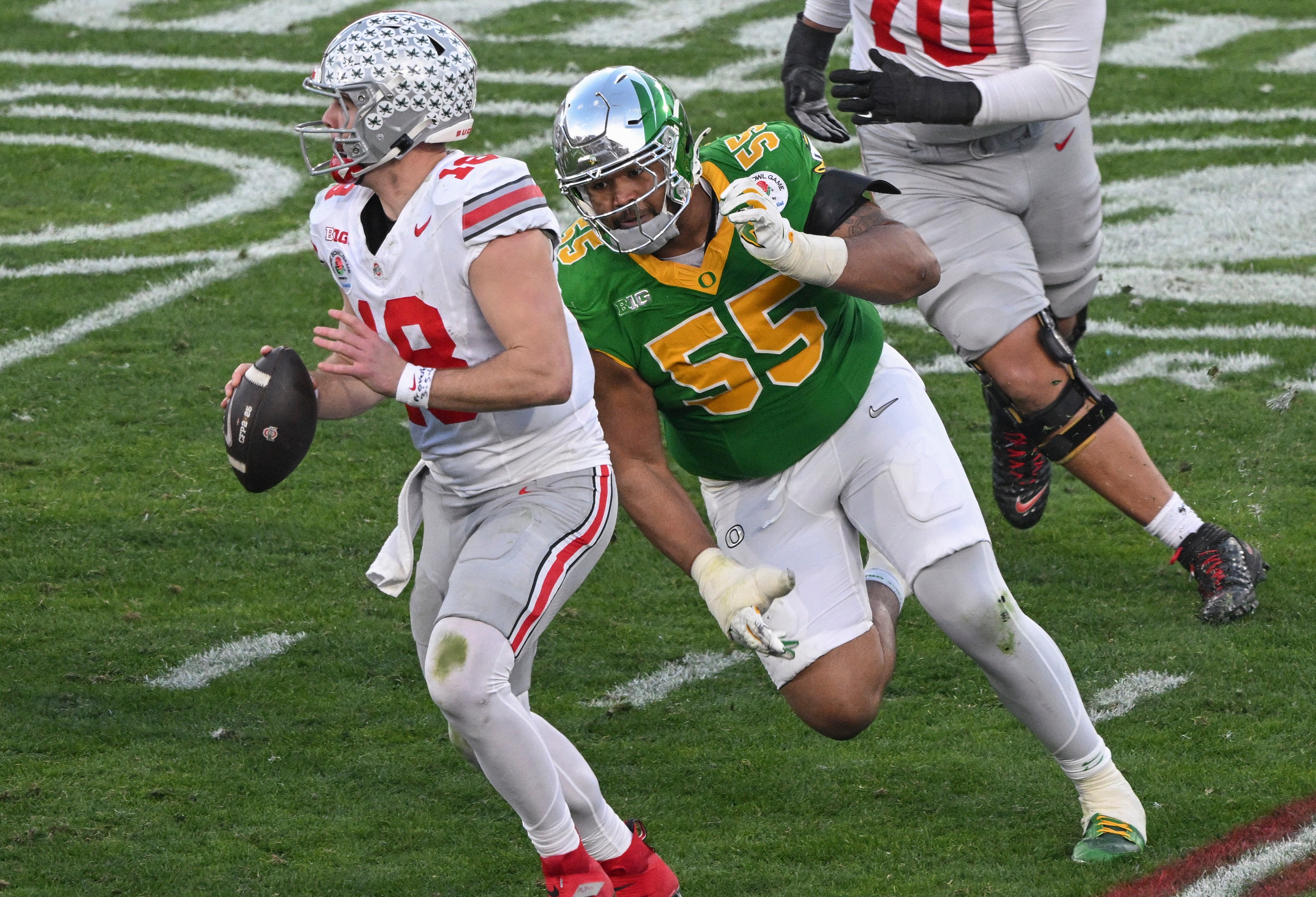 Jan 1, 2025; Pasadena, CA, USA; Ohio State Buckeyes quarterback Will Howard (18) looks for an open receiver as Oregon Ducks defensive lineman Derrick Harmon (55) closes in durigt the third quarter at Rose Bowl Stadium.