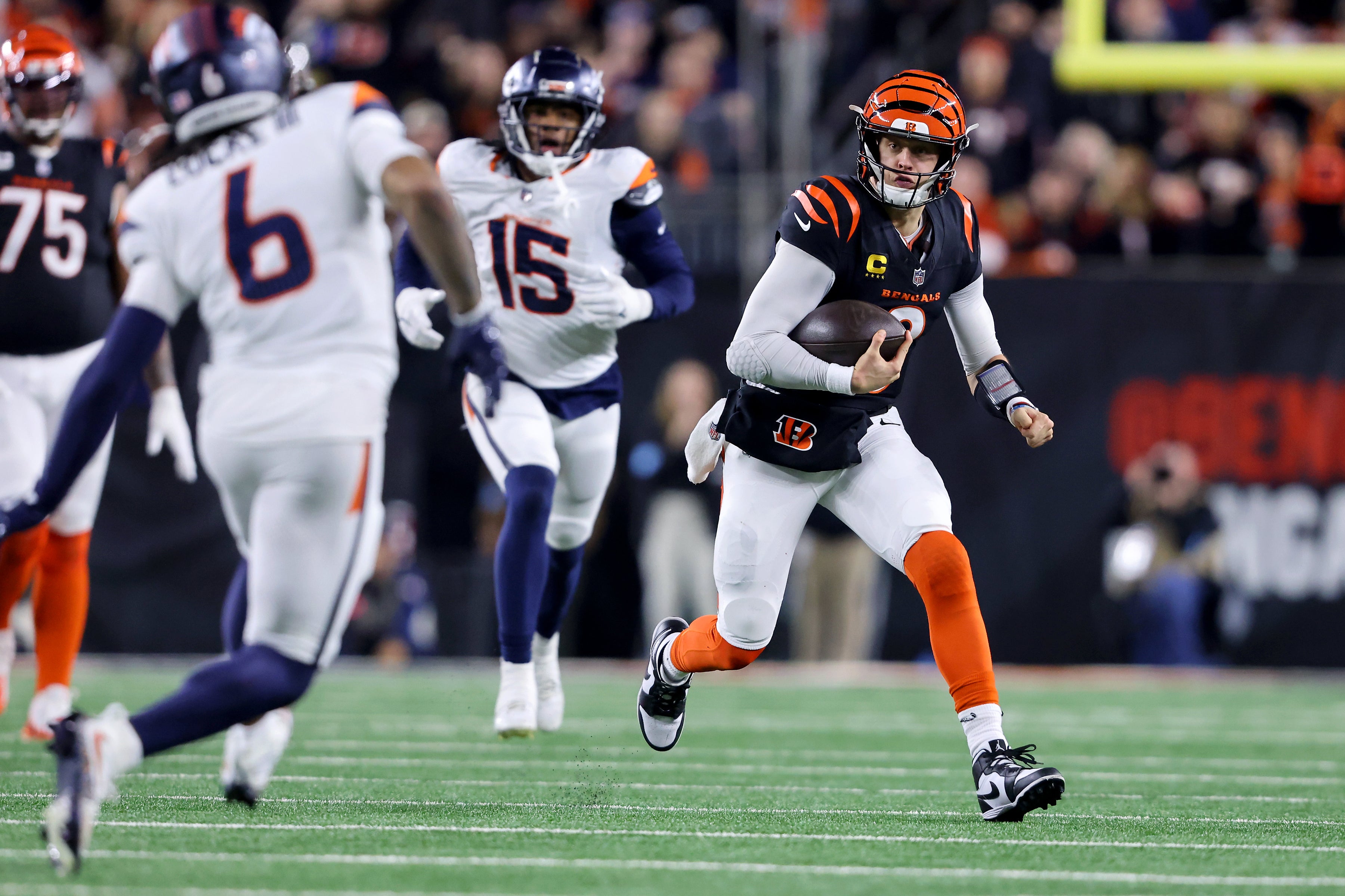Dec 28, 2024; Cincinnati, Ohio, USA; Cincinnati Bengals quarterback Joe Burrow (9) runs for a first down as Denver Broncos linebacker Nik Bonitto (15) chases him and safety P.J. Locke (6) makes the tackle during the fourth quarter at Paycor Stadium.