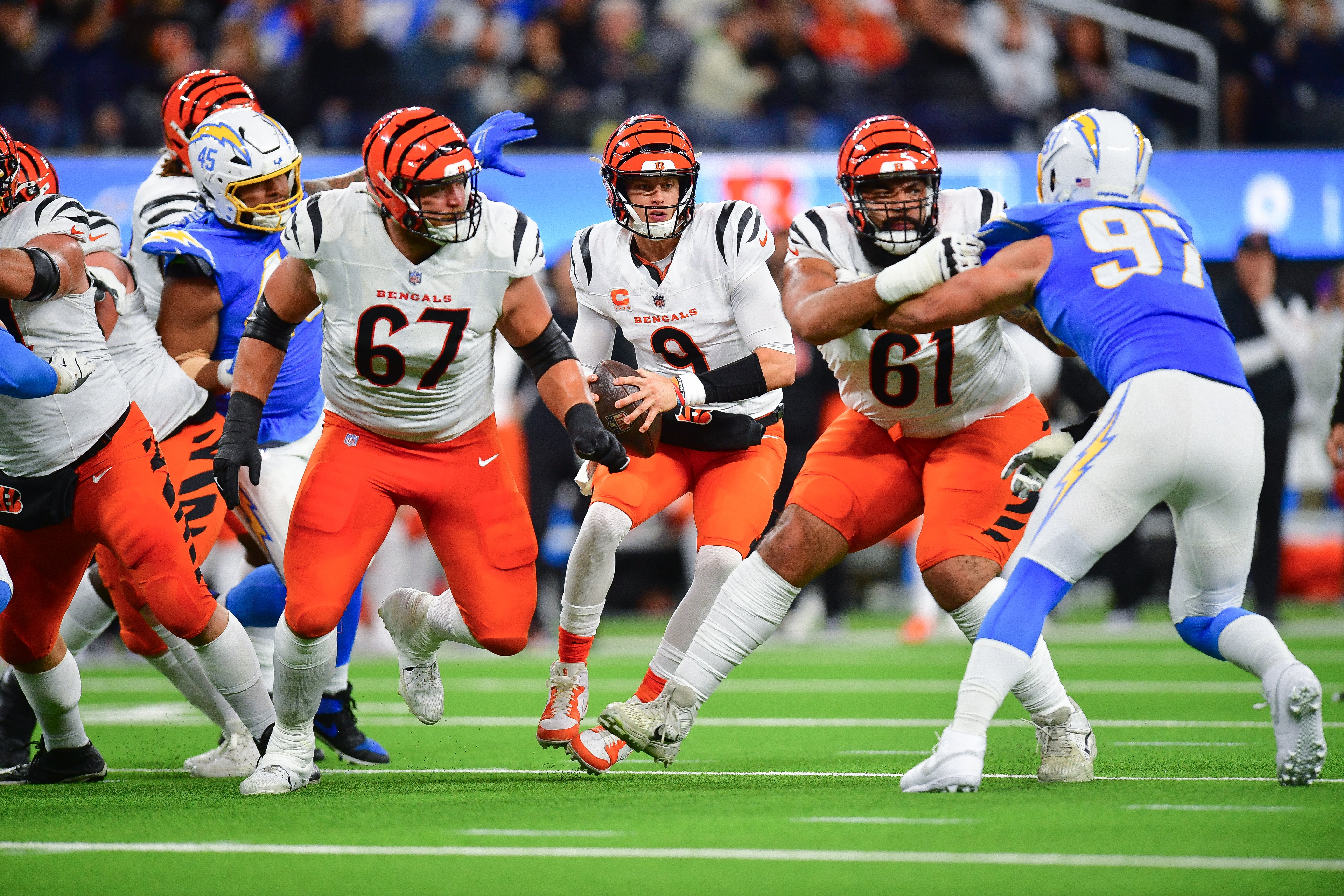 Nov 17, 2024; Inglewood, California, USA; Cincinnati Bengals quarterback Joe Burrow (9) moves out to pass as guard Cody Ford (61) and guard Cordell Volson (67) provide coverage against Los Angeles Chargers linebacker Joey Bosa (97) during the first half at SoFi Stadium.