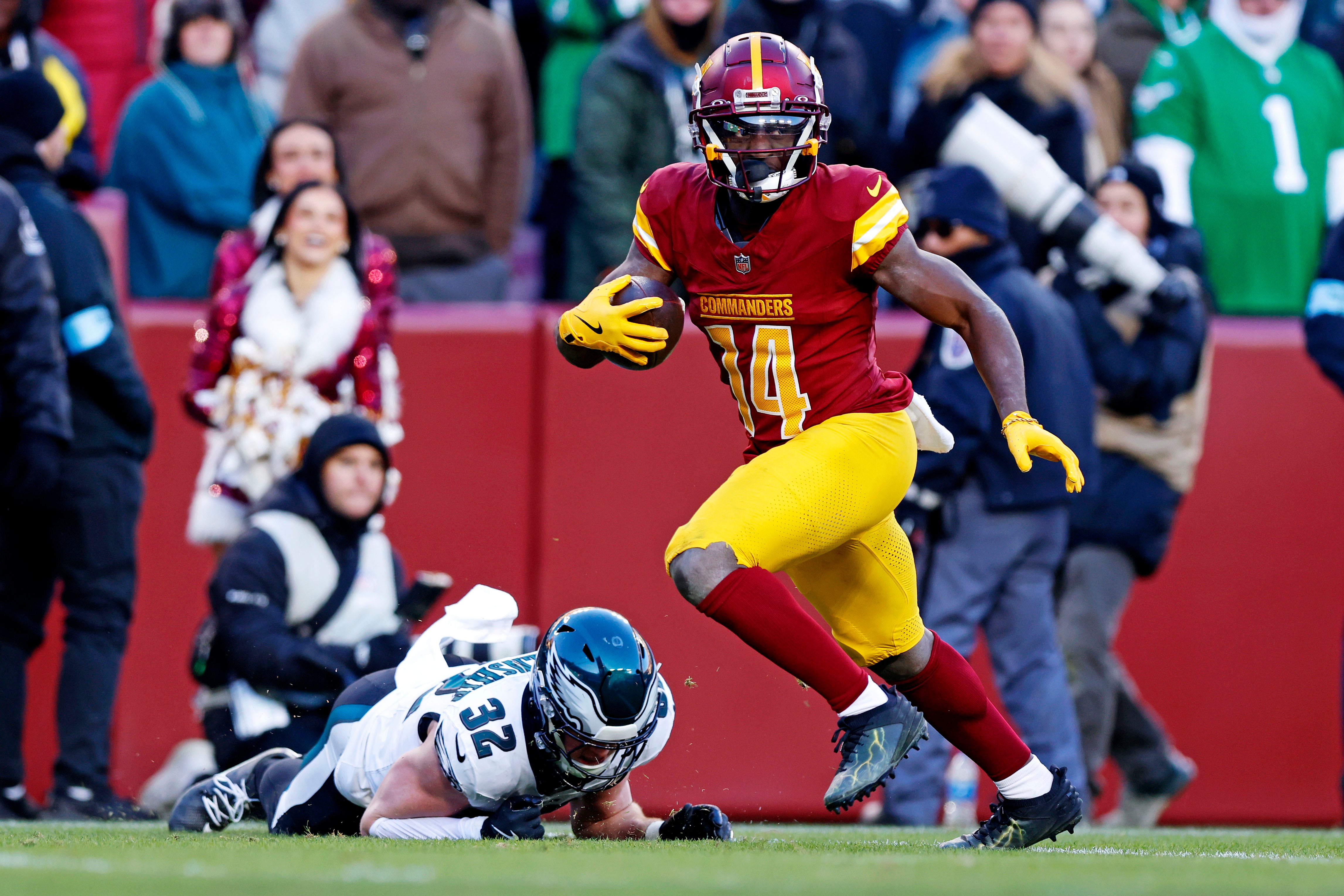 Dec 22, 2024; Landover, Maryland, USA; Washington Commanders wide receiver Olamide Zaccheaus (14) breaks a tackle by Philadelphia Eagles safety Reed Blankenship (32) to score a touchdown during the fourth quarter at Northwest Stadium.