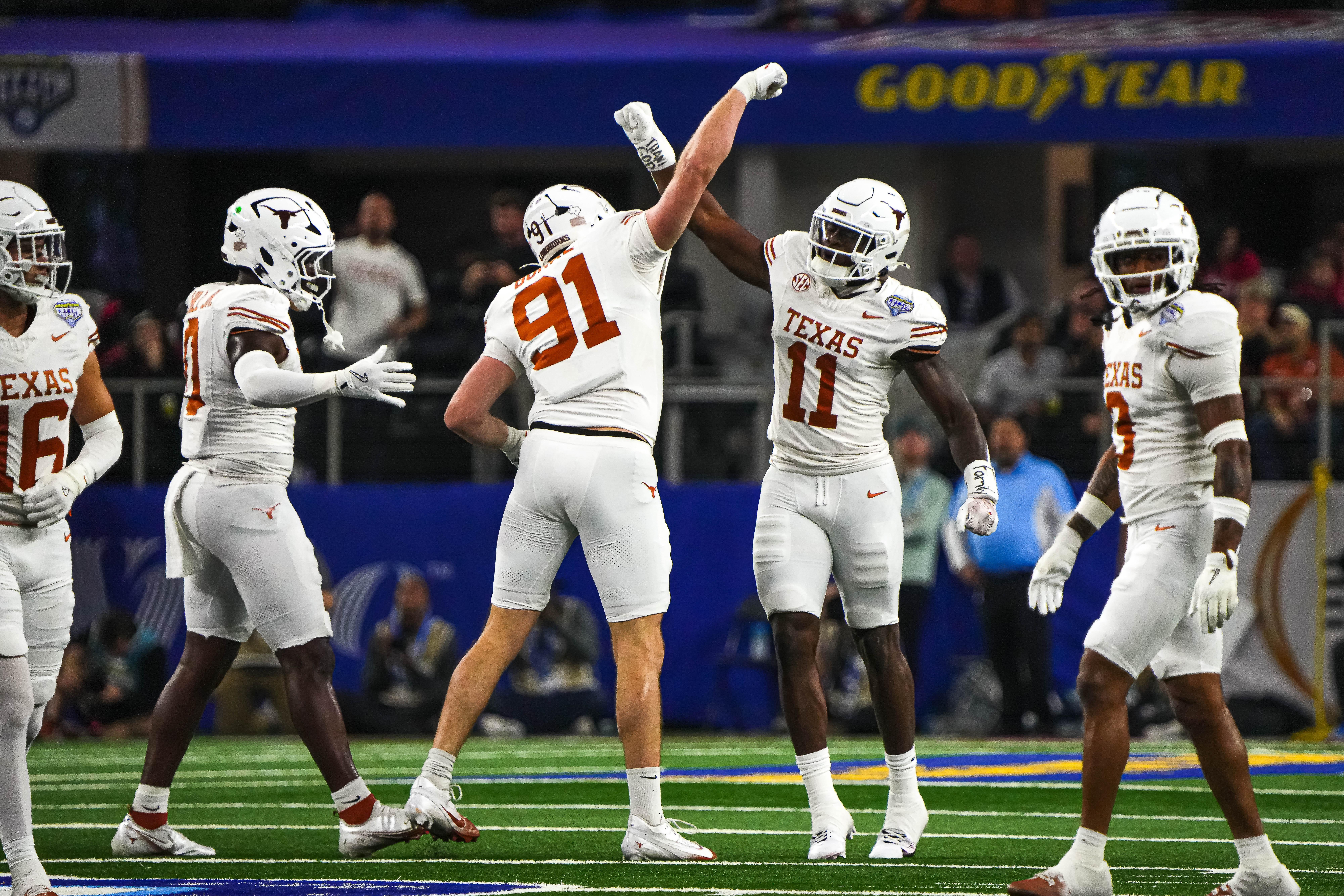 Texas Longhorns edge rushers Colin Simmons (11) and Ethan Burke (91) celebrate a sack during the College Football Playoff semifinal game against Ohio State in the Cotton Bowl at AT&T Stadium on Friday, Jan. 10, 2024 in Arlington, Texas.