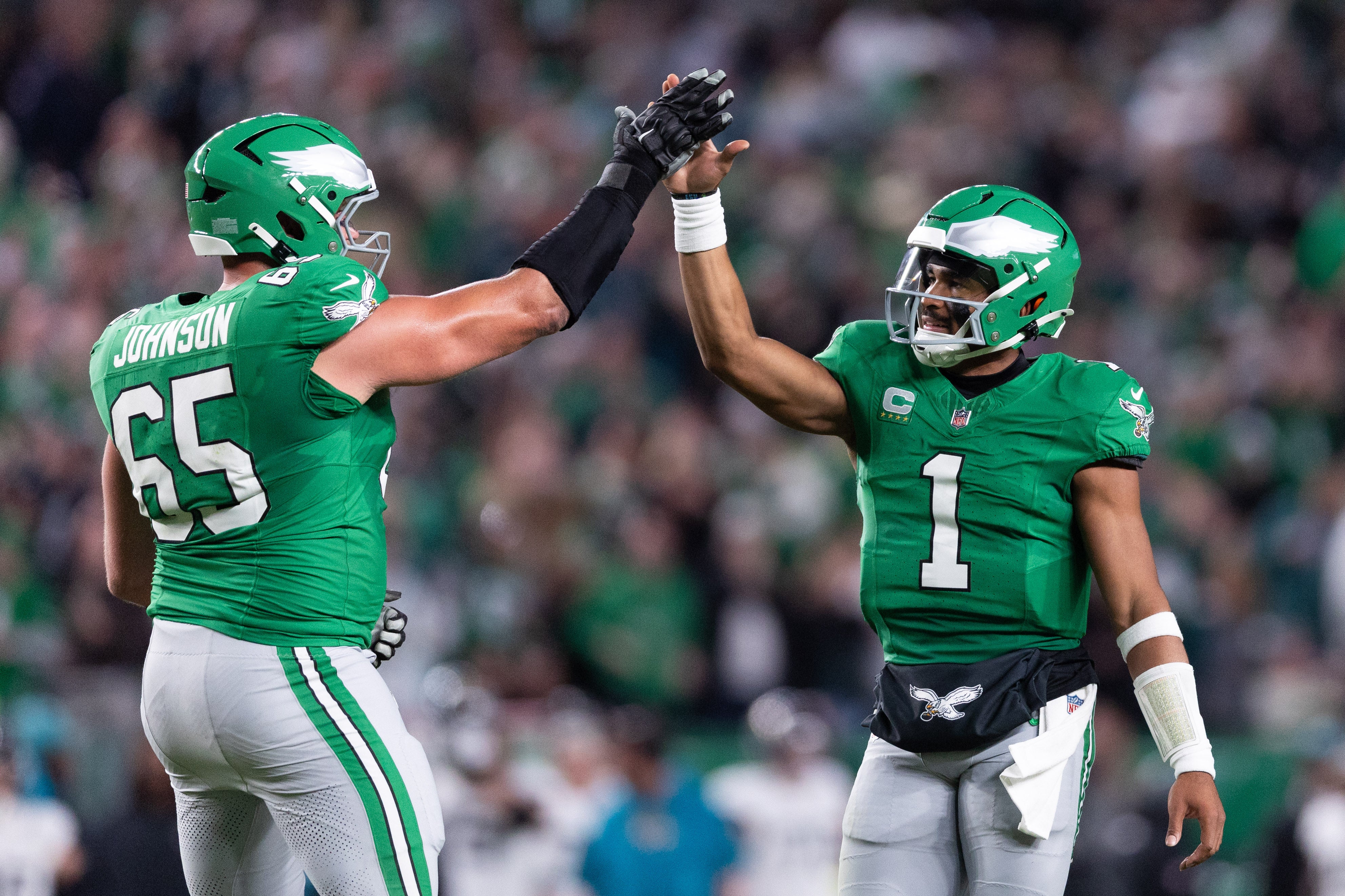 Philadelphia Eagles quarterback Jalen Hurts (1) and offensive tackle Lane Johnson (65) high five after a Saquon Barkley (not pictured) touchdown run against the Jacksonville Jaguars.