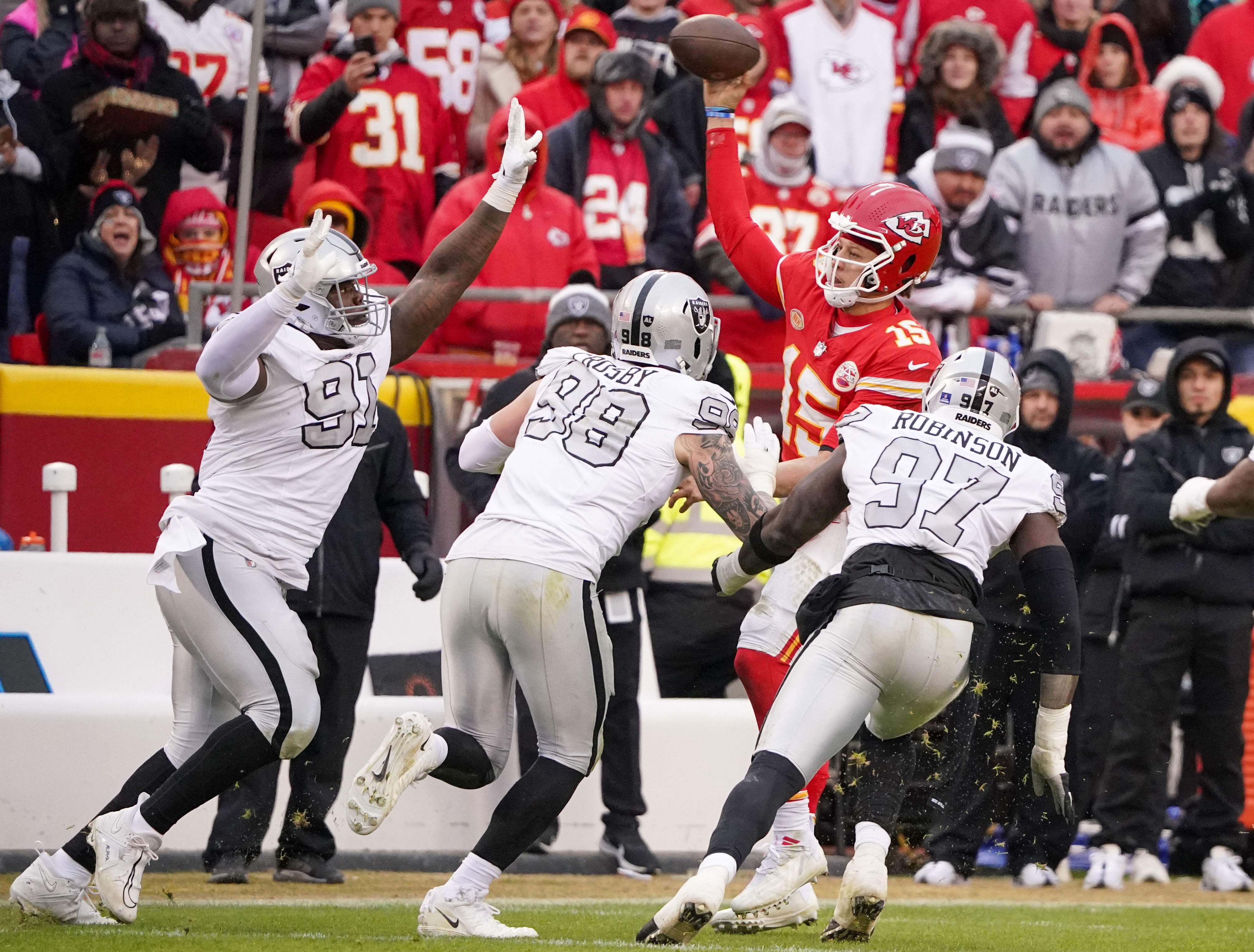 Dec 25, 2023; Kansas City, Missouri, USA; Kansas City Chiefs quarterback Patrick Mahomes (15) throws a pass as he s pressured by Las Vegas Raiders defensive tackle Bilal Nichols (91) and defensive end Maxx Crosby (98) and defensive end Janarius Robinson (97) during the game at GEHA Field at Arrowhead Stadium.