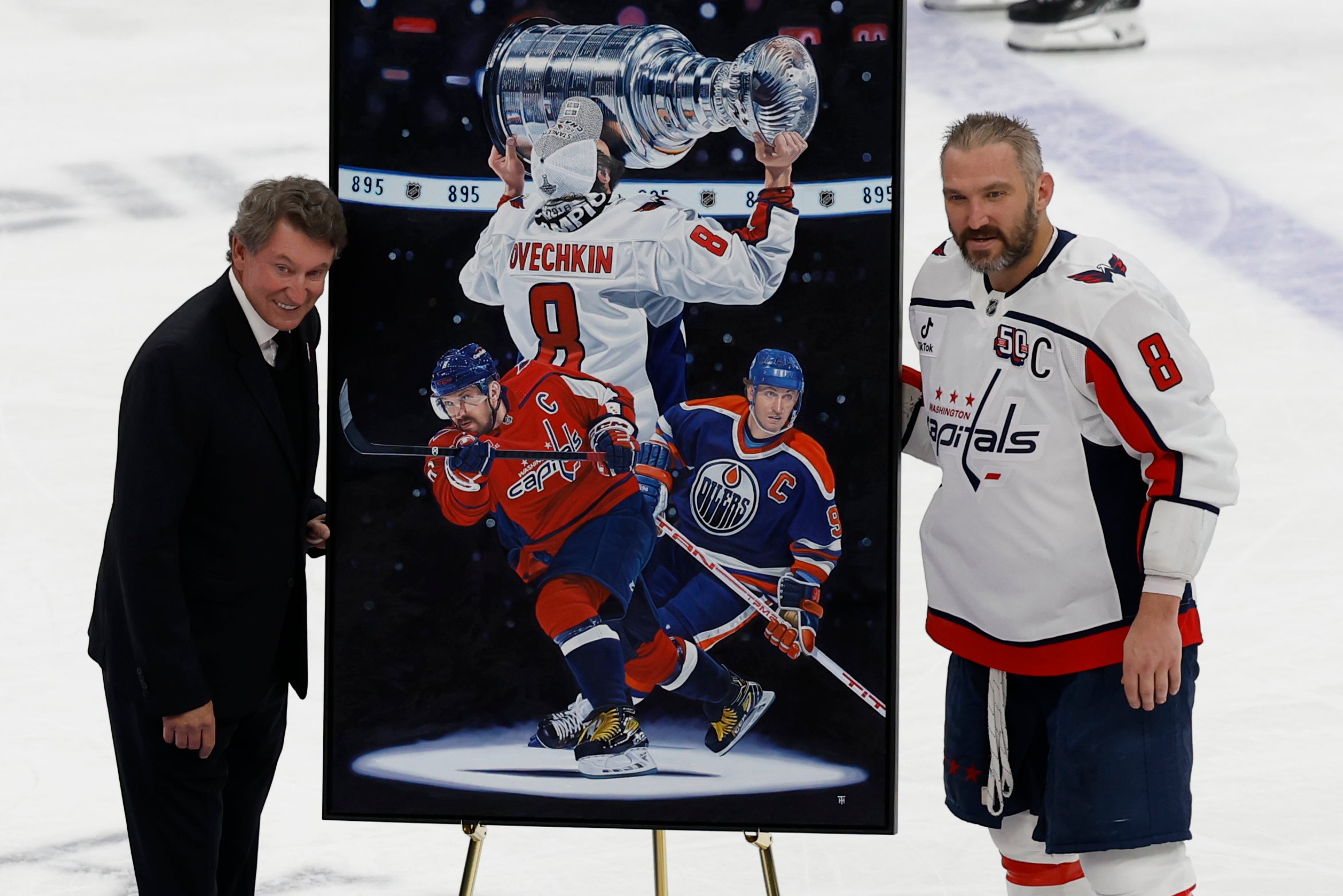 Apr 6, 2025; Elmont, New York, USA; Washington Capitals left wing Alex Ovechkin (8) is honored with a painting by artist Tony Harris by former Canadian-American ice hockey player Wayne Gretzky after scoring in the during the second period against the New York Islanders at UBS Arena. Ovechkin scored the 895th goal of his career, breaking the NHL all-time career goals record previously held by Wayne Gretzky at UBS Arena.