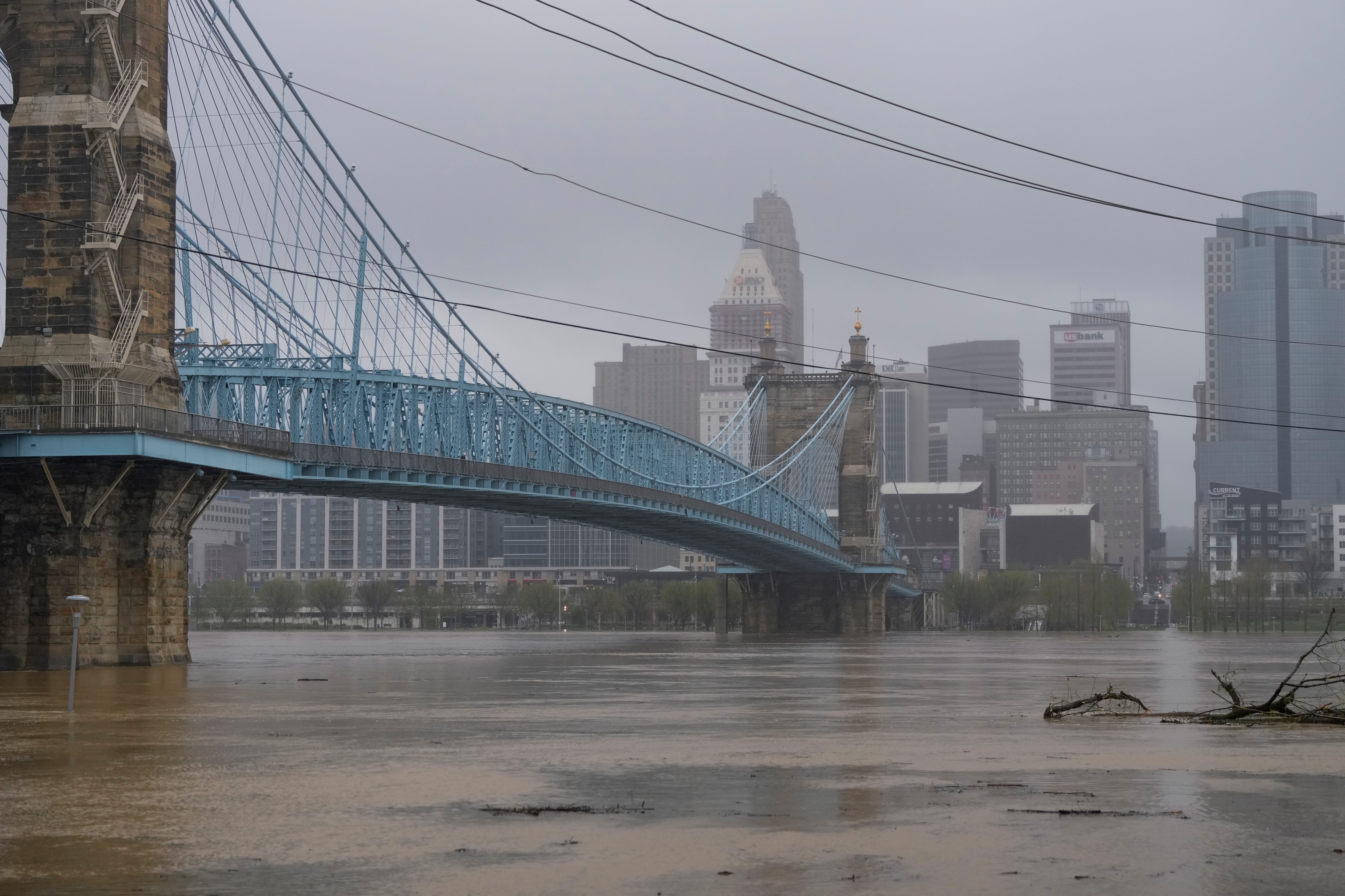 The flooded Ohio River flows under the John A. Roebling Suspension Bridge in front of Cincinnati on Sunday, April 6, 2025.