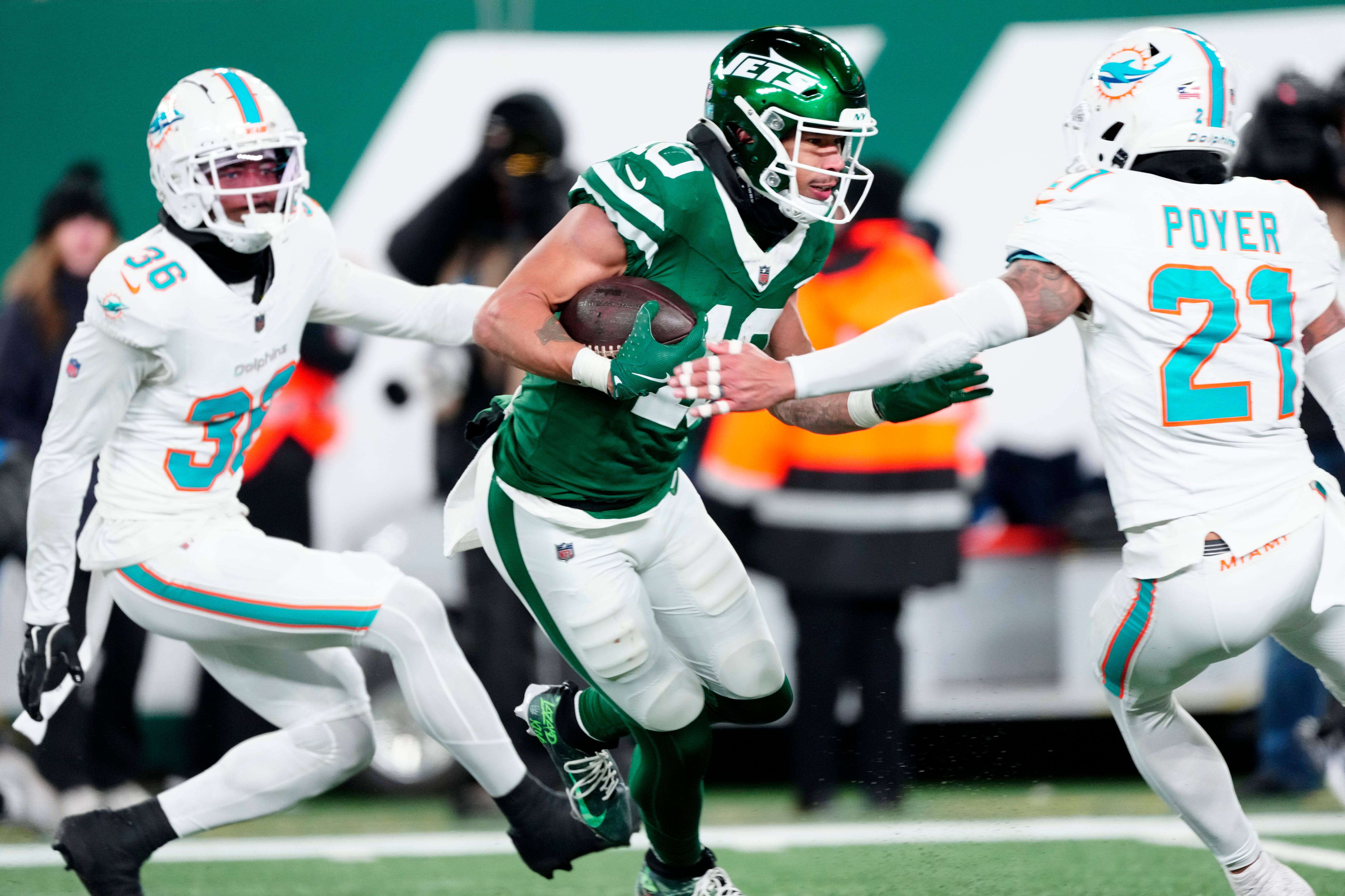 New York Jets wide receiver Allen Lazard (10) runs with the ball between Miami Dolphins cornerback Storm Duck (36) and Miami Dolphins safety Jordan Poyer (21), Sunday January 5, 2025, in East Rutherford.