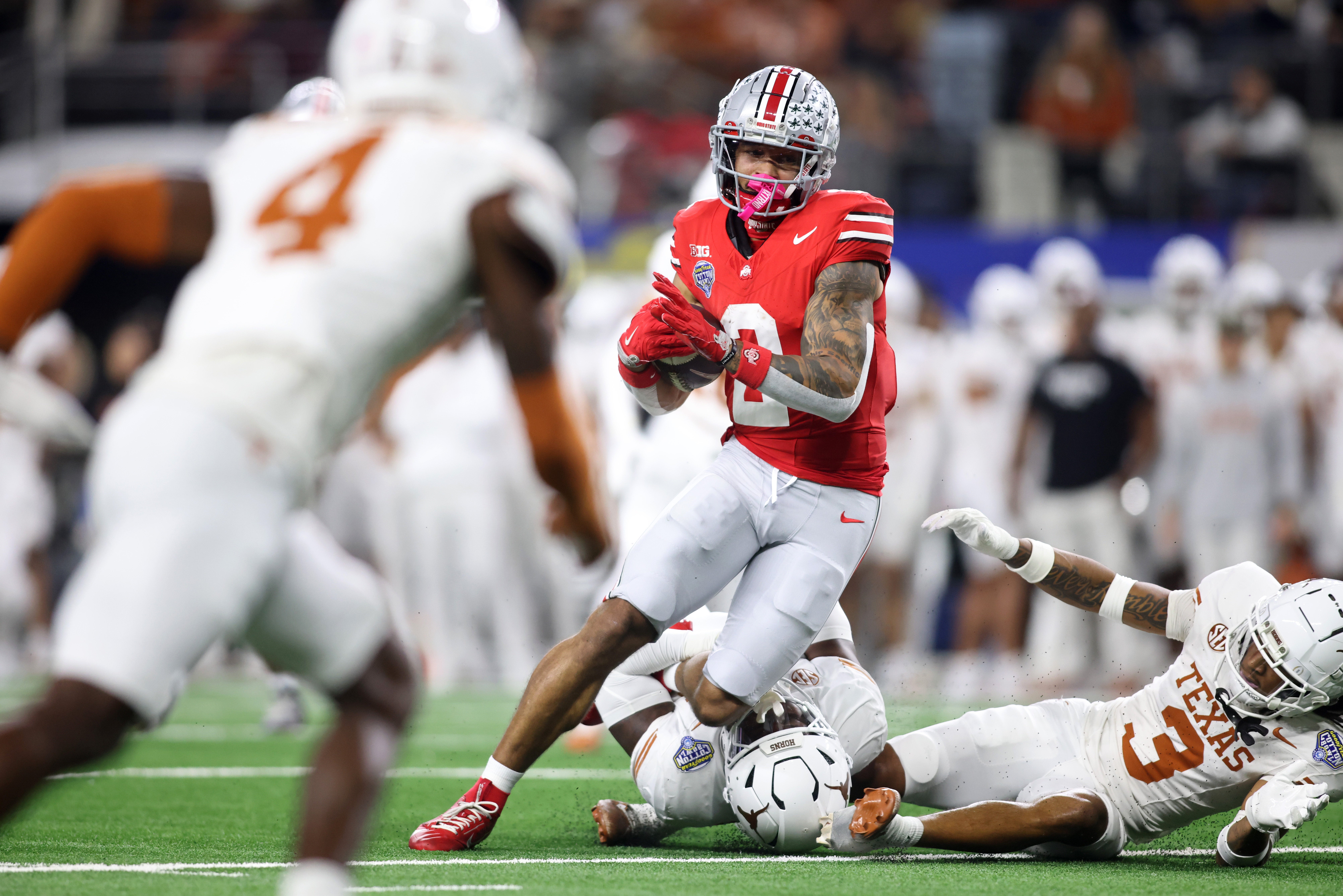 Ohio State Buckeyes wide receiver Emeka Egbuka (2) runs against Texas Longhorns defensive back Jaylon Guilbeau (3) during the first quarter of the College Football Playoff semifinal in the Cotton Bowl at AT&T Stadium.