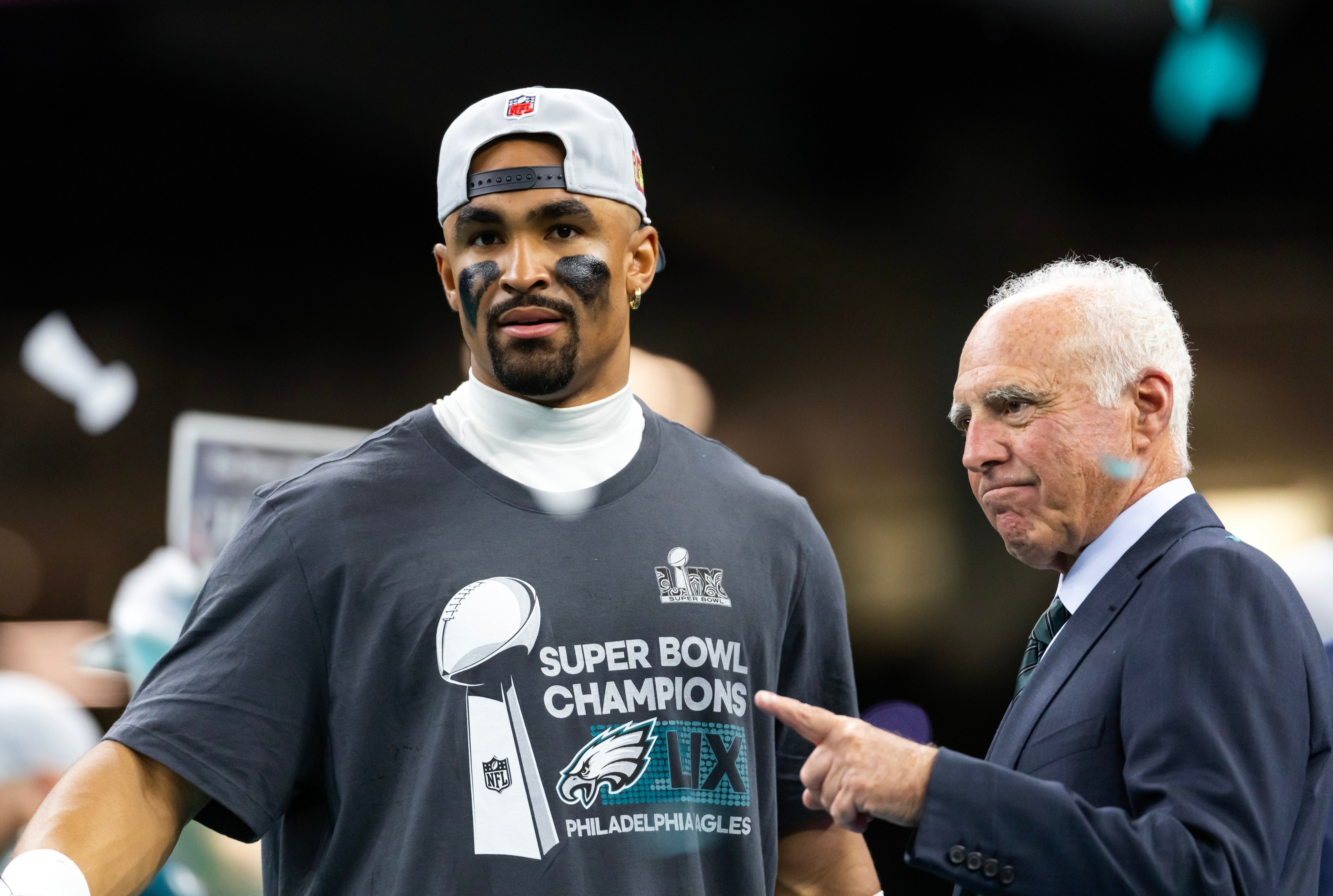 Philadelphia Eagles quarterback Jalen Hurts (left) celebrates with owner Jeffrey Lurie after defeating the Kansas City Chiefs to win Super Bowl LIX at Ceasars Superdome.