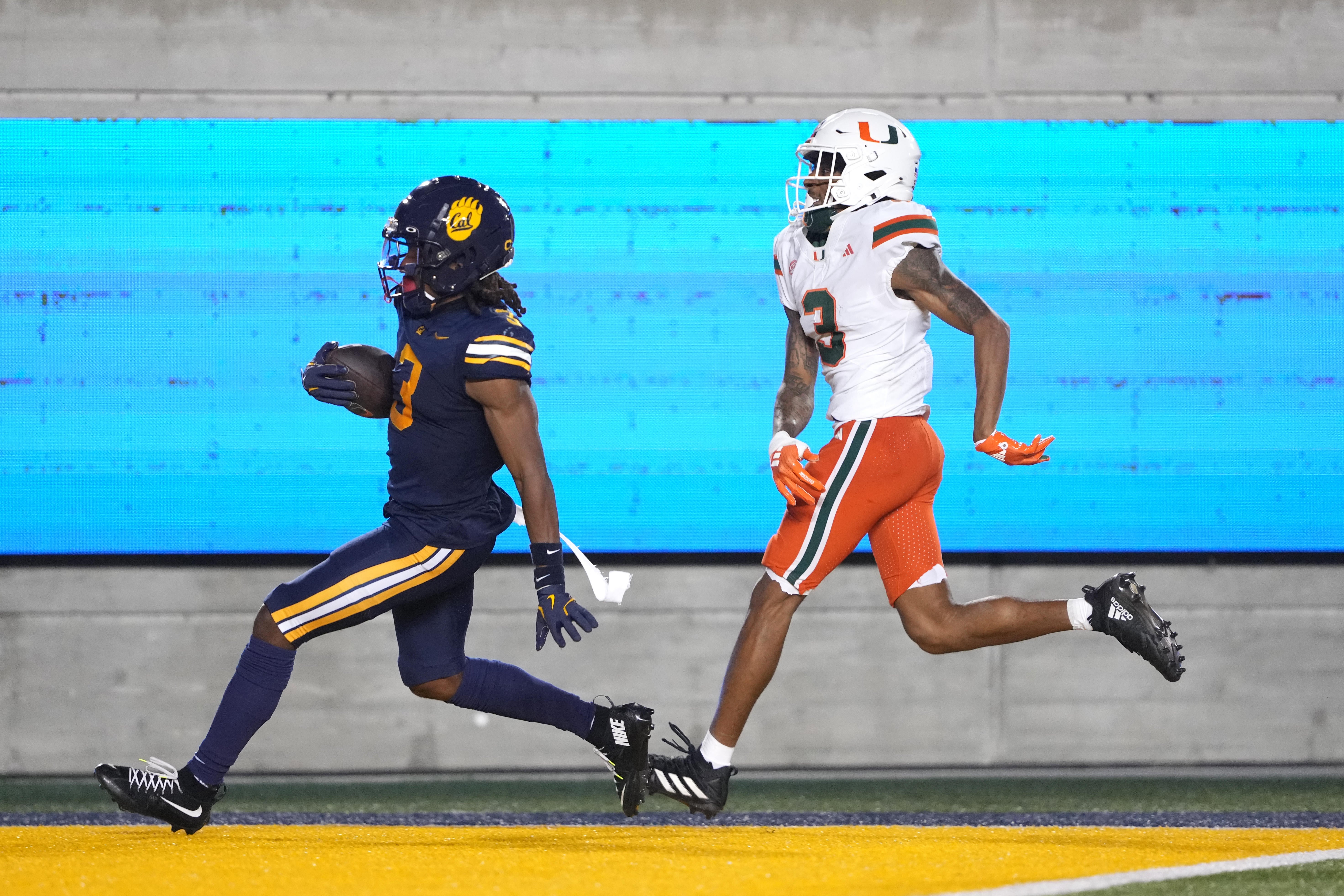 Oct 5, 2024; Berkeley, California, USA; California Golden Bears defensive back Nohl Williams (left) scores a touchdown against Miami Hurricanes wide receiver Jacolby George (right) after intercepting a pass during the third quarter at California Memorial Stadium.
