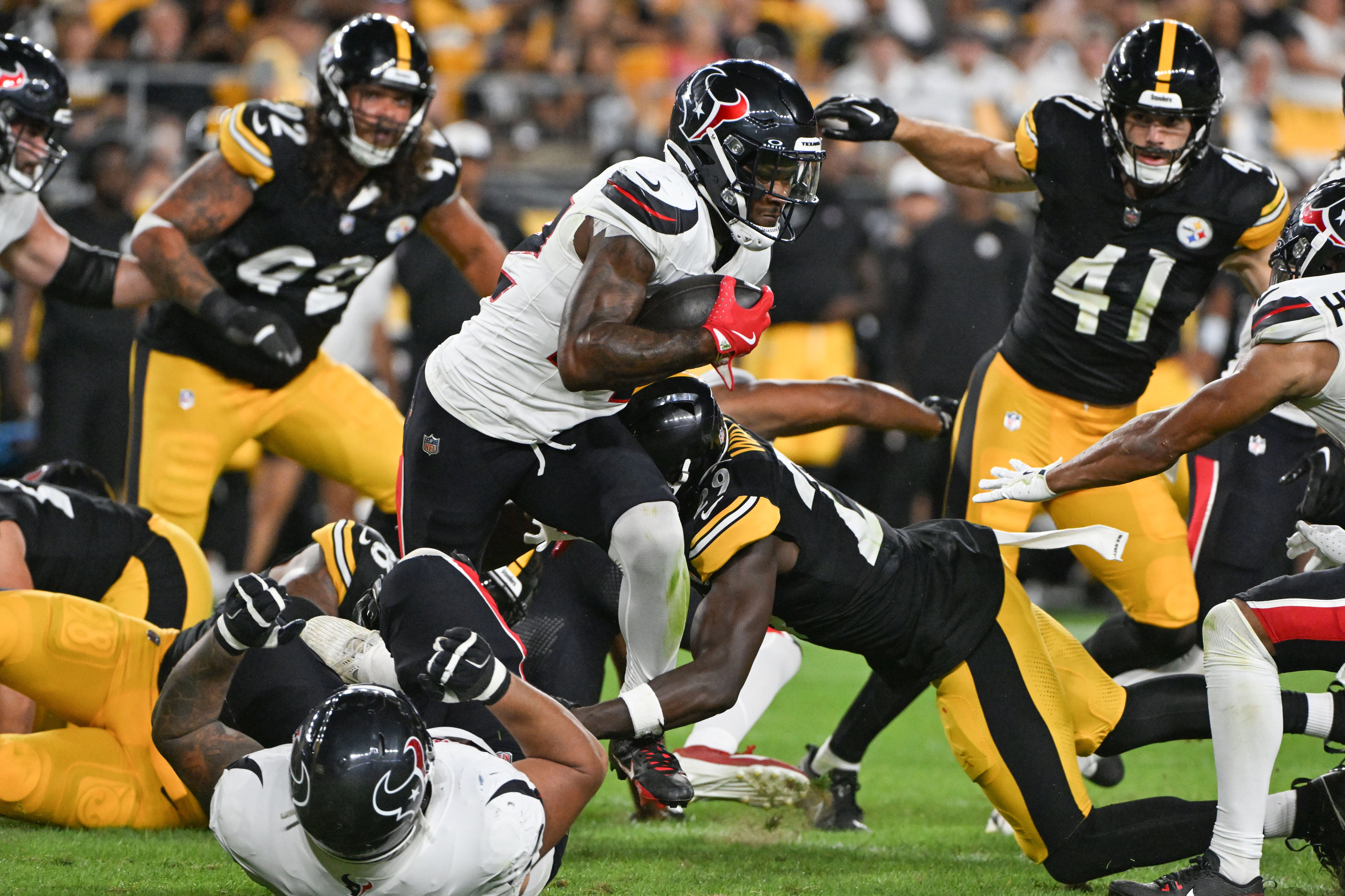 Aug 9, 2024; Pittsburgh, Pennsylvania, USA; Houston Texans running back Cam Akers breaks a tackle attempt by Pittsburgh Steelers cornerback Ryan Watts (29) during the third quarter at Acrisure Stadium.
