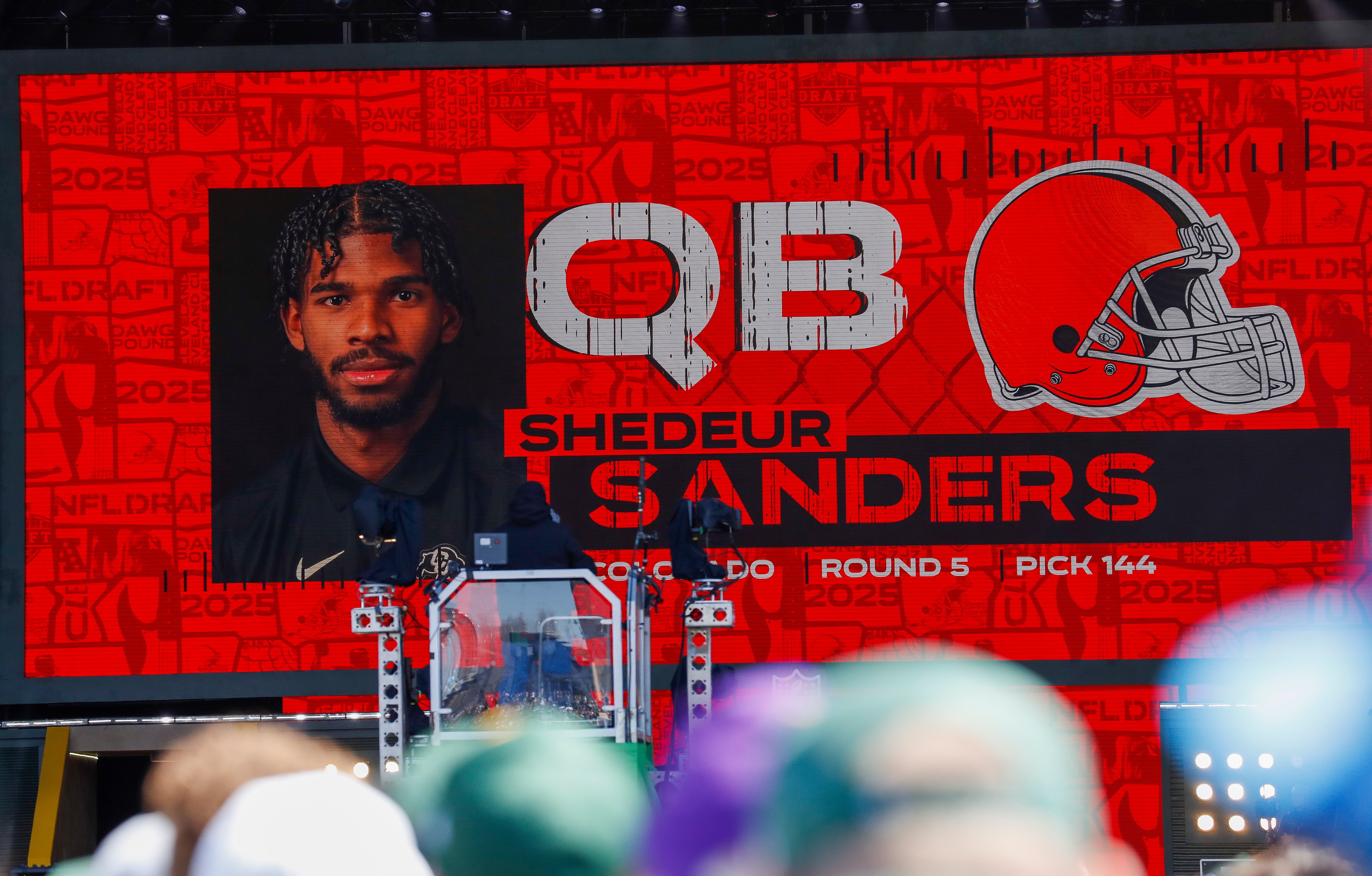 Apr 25, 2025; Green Bay, WI, USA; A graphic announcing Colorado quarterback Shedeur Sanders’ selection by the Cleveland Browns with the 144th overall pick is seen in the Draft Theater during the third day of the 2025 NFL Draft at Lambeau Field.