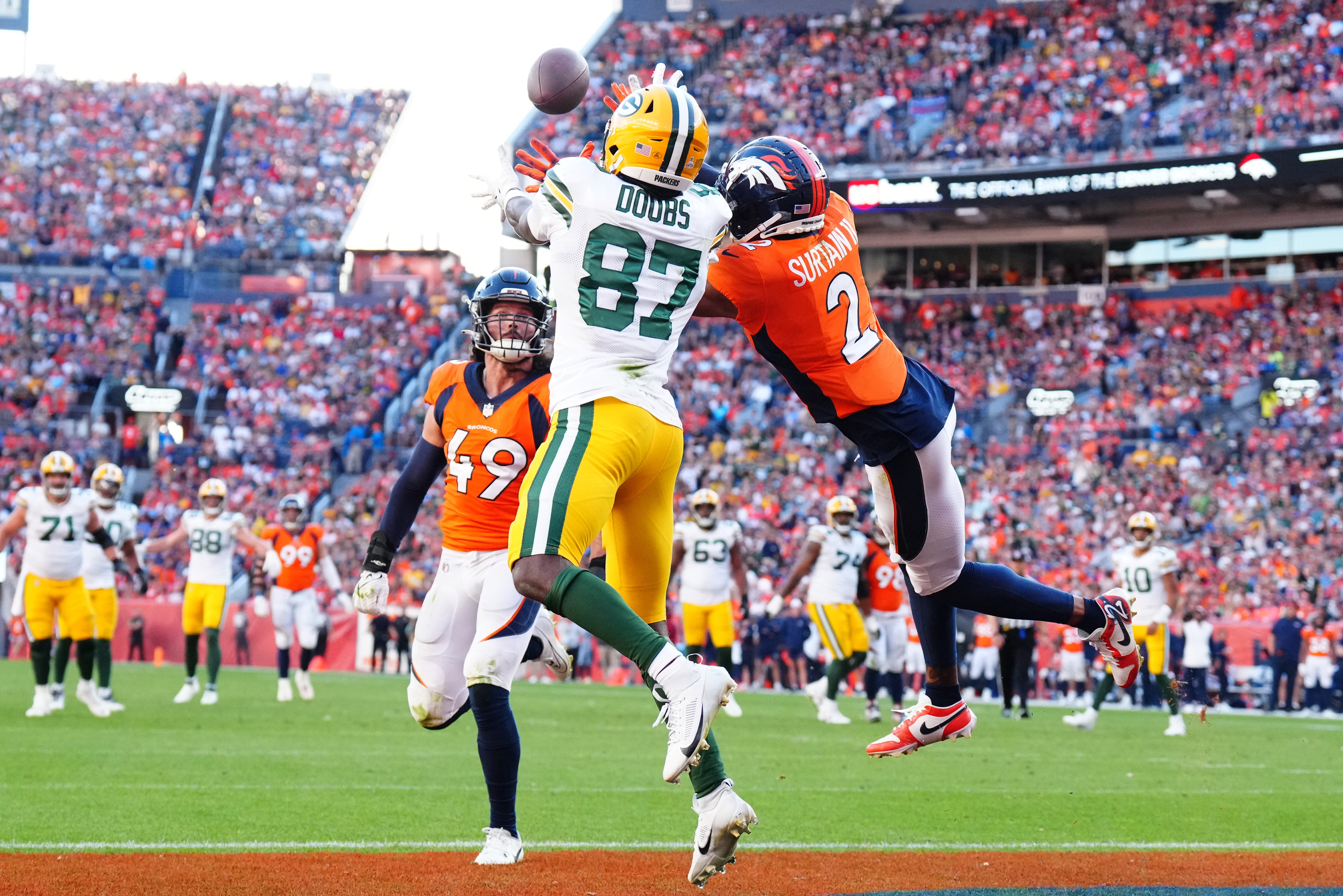 Green Bay Packers wide receiver Romeo Doubs (87) pulls in a touchdown past Denver Broncos cornerback Pat Surtain II (2) and linebacker Alex Singleton (49) in the fourth quarter at Empower Field at Mile High.