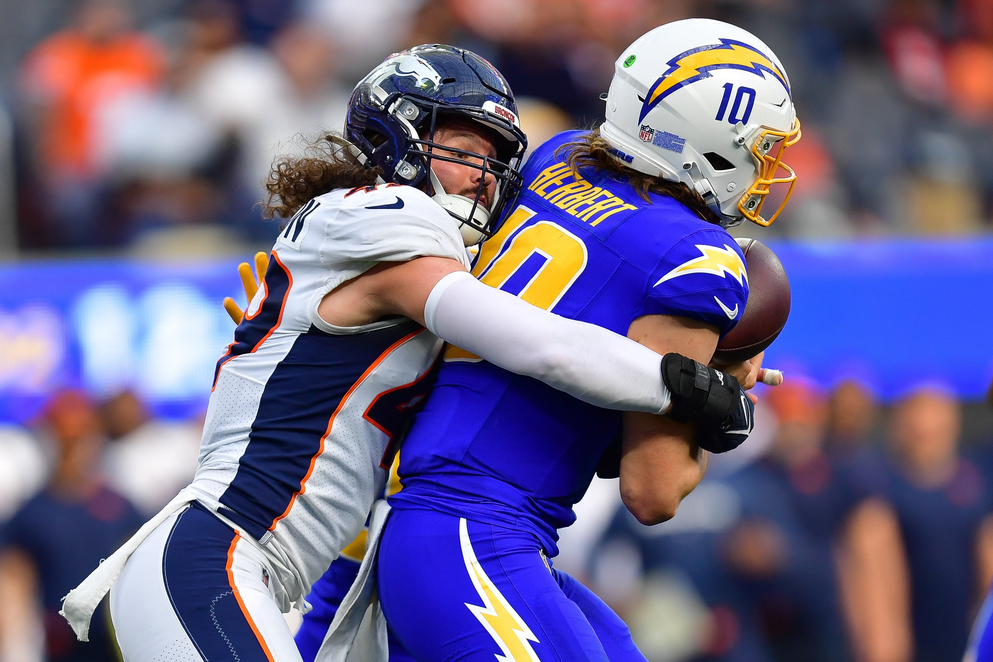 Denver Broncos linebacker Alex Singleton (49) brings down Los Angeles Chargers quarterback Justin Herbert (10) 