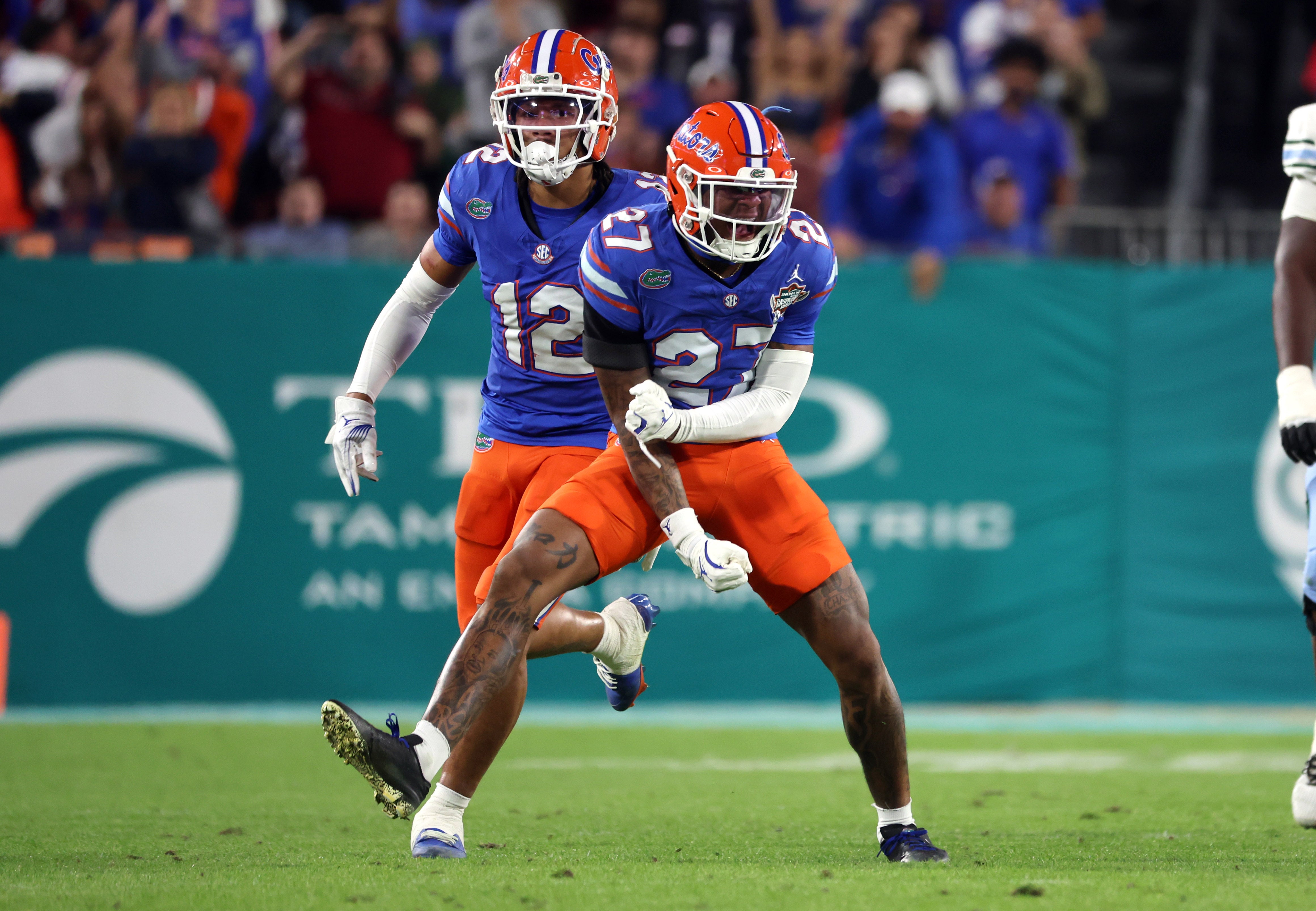 Dec 20, 2024; Tampa, FL, USA; Florida Gators defensive back Dijon Johnson (27) and defensive back DJ Douglas (12) celebrate after they made a tackle against the Tulane Green Wave during the second half at Raymond James Stadium.