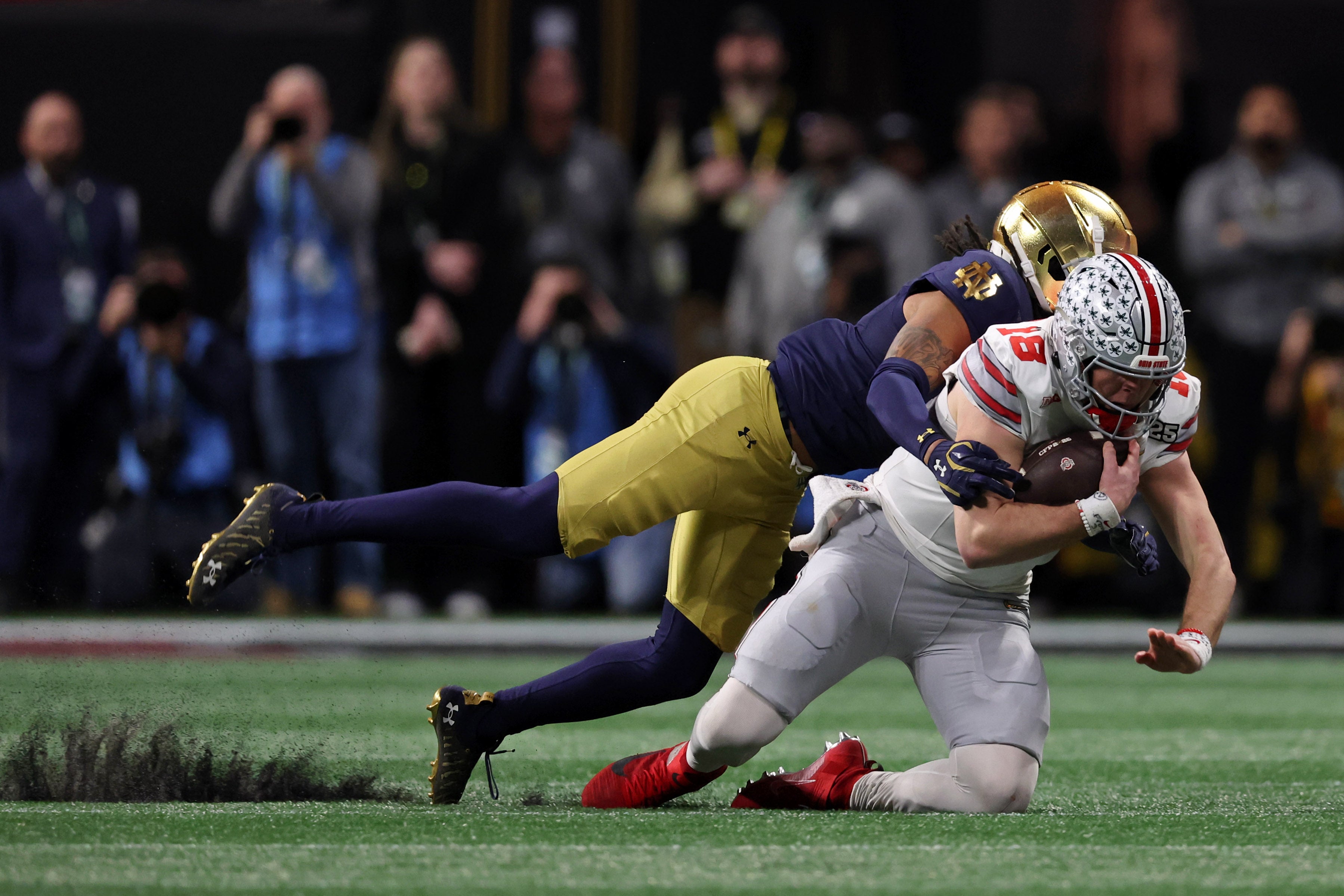Jan 20, 2025; Atlanta, GA, USA; Notre Dame Fighting Irish safety Xavier Watts (0) tackles Ohio State Buckeyes quarterback Will Howard (18) during the second half the CFP National Championship college football game at Mercedes-Benz Stadium. Mandatory Credit: Brett Davis-Imagn Images