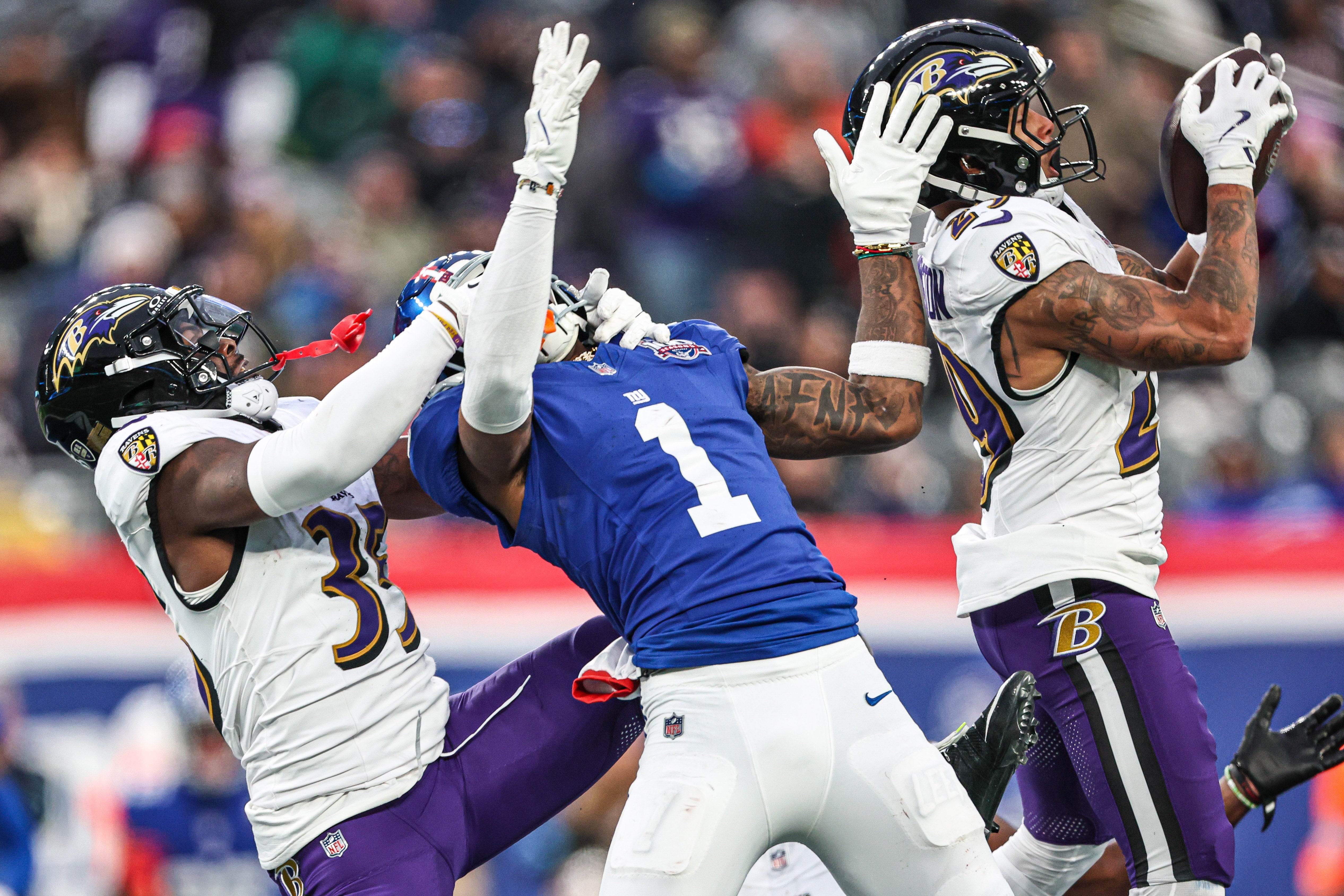 Baltimore Ravens safety Ar'Darius Washington (29) intercepts a pass intended for New York Giants wide receiver Malik Nabers (1) as cornerback Desmond King II (35) tackles