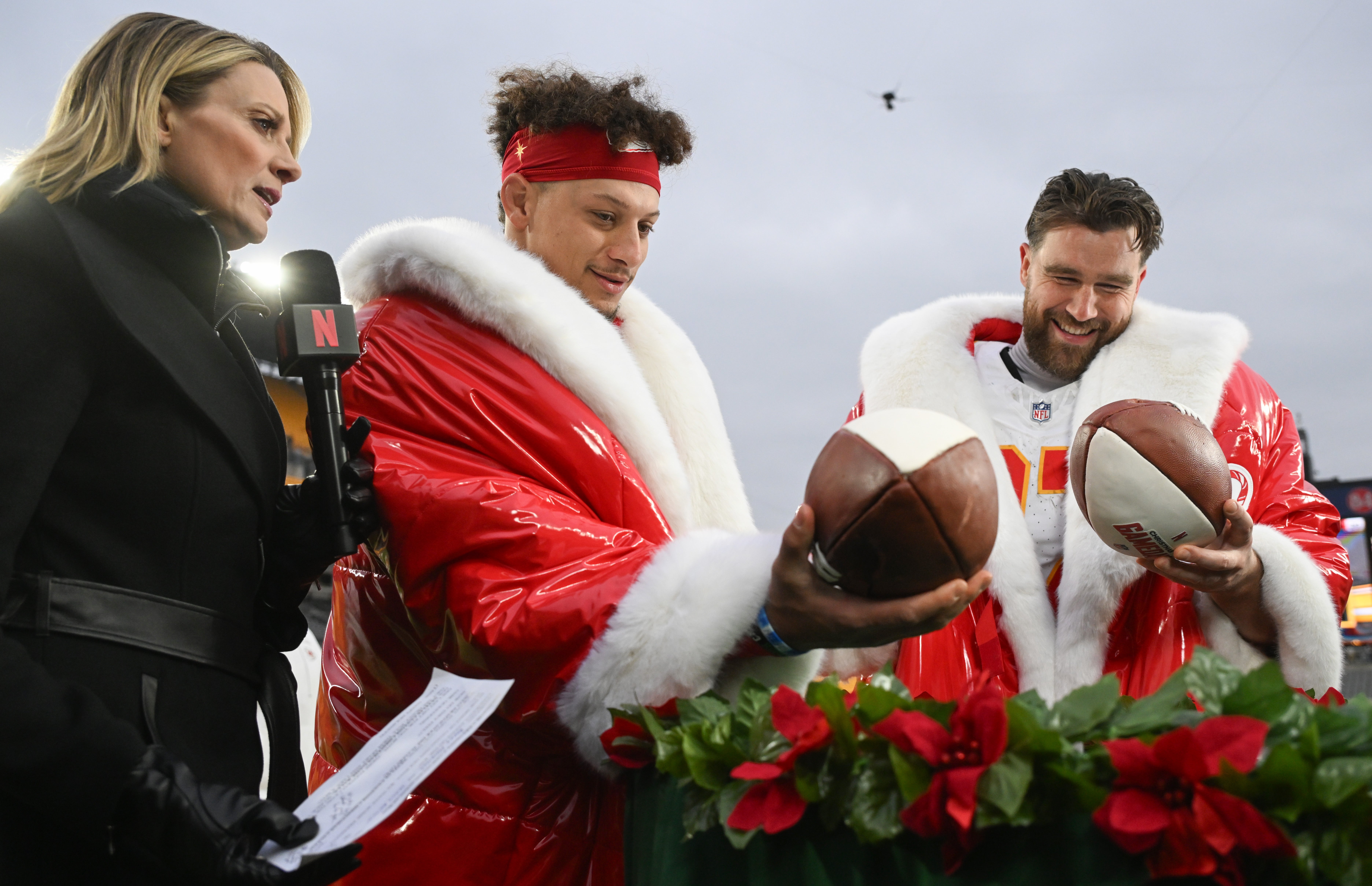 Dec 25, 2024; Pittsburgh, Pennsylvania, USA; Kansas City Chiefs quarterback Patrick Mahomes (15) and tight end Travis Kelce (87) look at football cakes while being interviewed by Netflix reporter Stacey Dales following their win against the Pittsburgh Steelers at Acrisure Stadium.