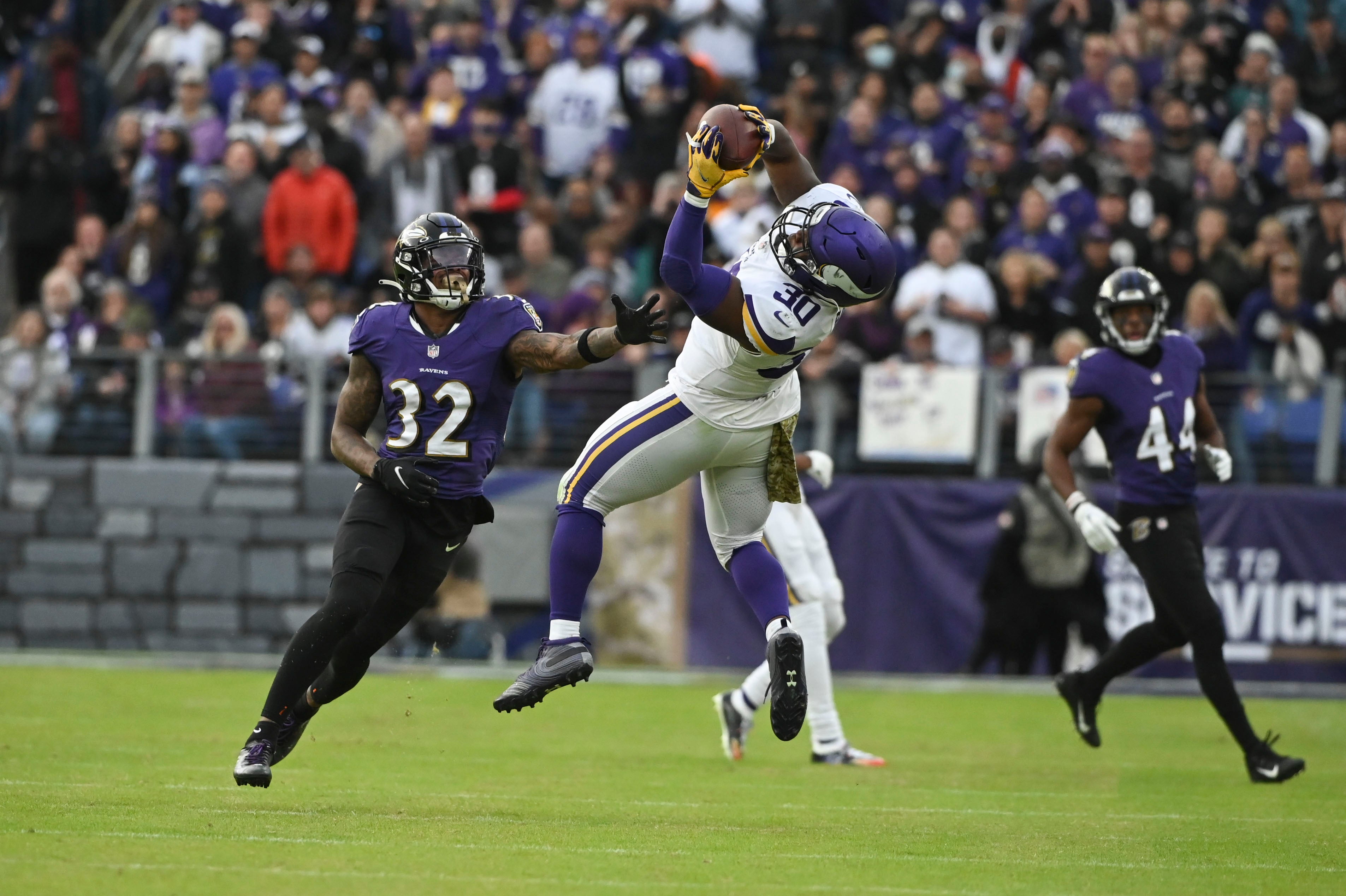 Nov 7, 2021; Baltimore, Maryland, USA; Minnesota Vikings fullback C.J. Ham (30) leaps to catch a pass in front of Baltimore Ravens free safety DeShon Elliott (32) during the second half at M&T Bank Stadium.