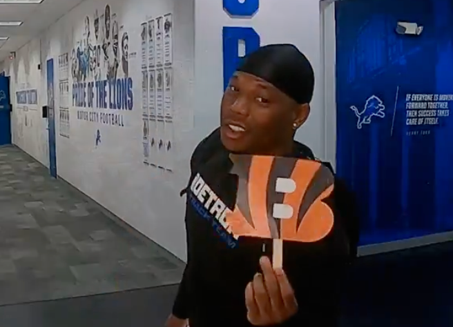 Detroit Lions running back David Montgomery holds up a Cincinnati Bengals logo for a social media post.
