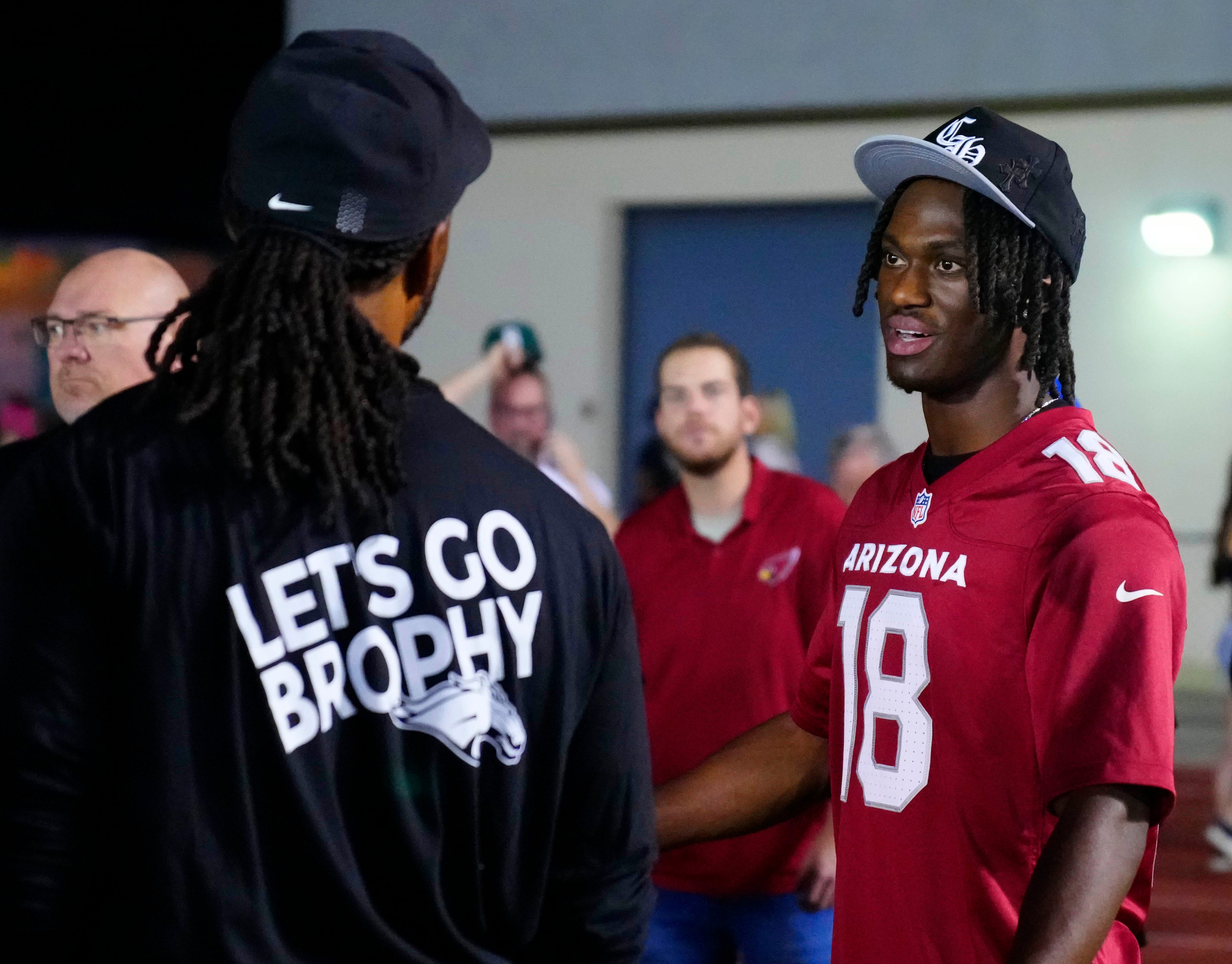 Cardinals legend Larry Fitzgerald (left) and current wide receiver Marvin Harrison Jr. (18) hang out on the sidelines during a high school game at Central High School