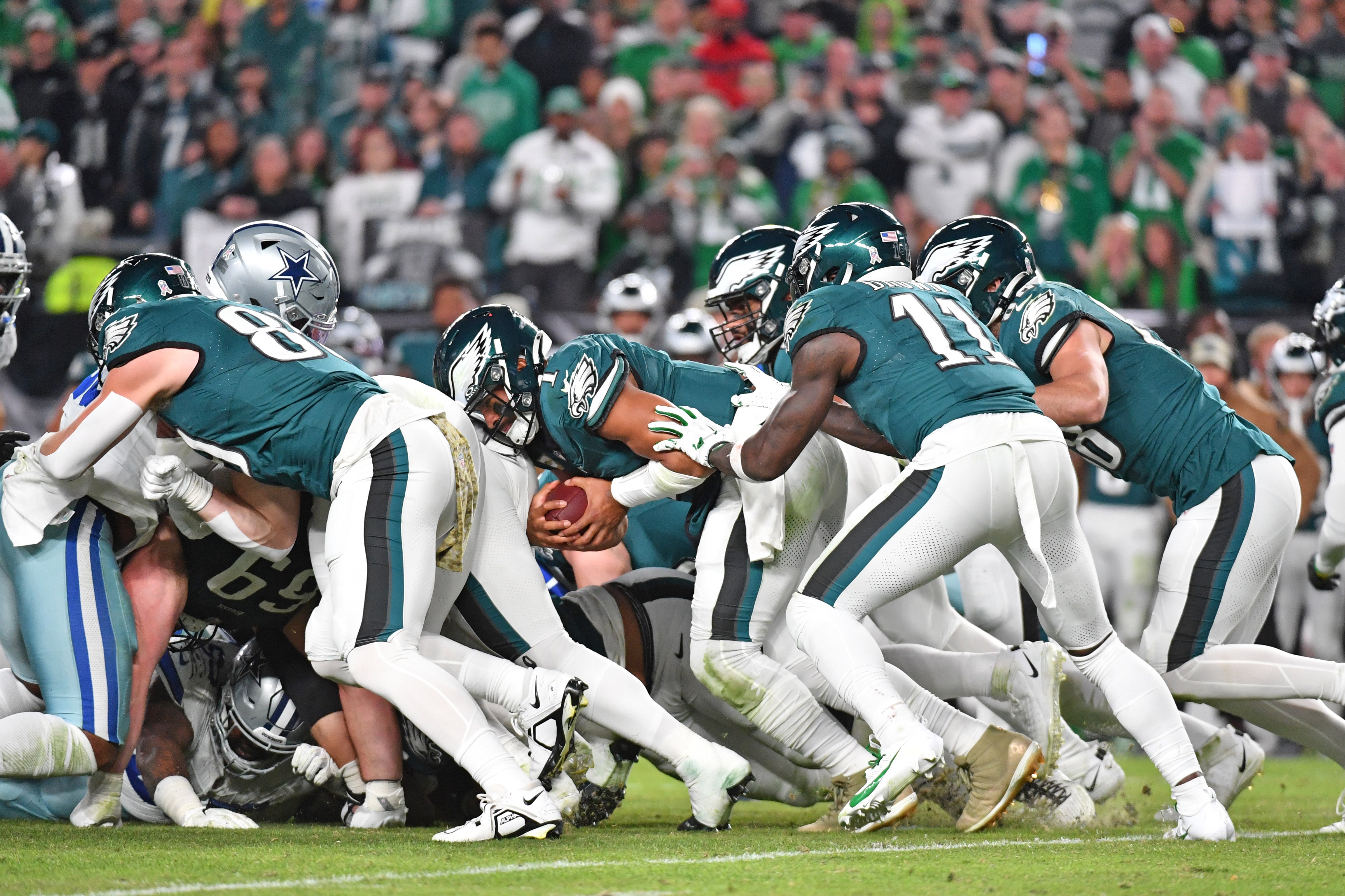 Philadelphia Eagles quarterback Jalen Hurts (1) picks up yardage a first down with a push from wide receiver A.J. Brown (11) and tight end Dallas Goedert (88) against the Dallas Cowboys.