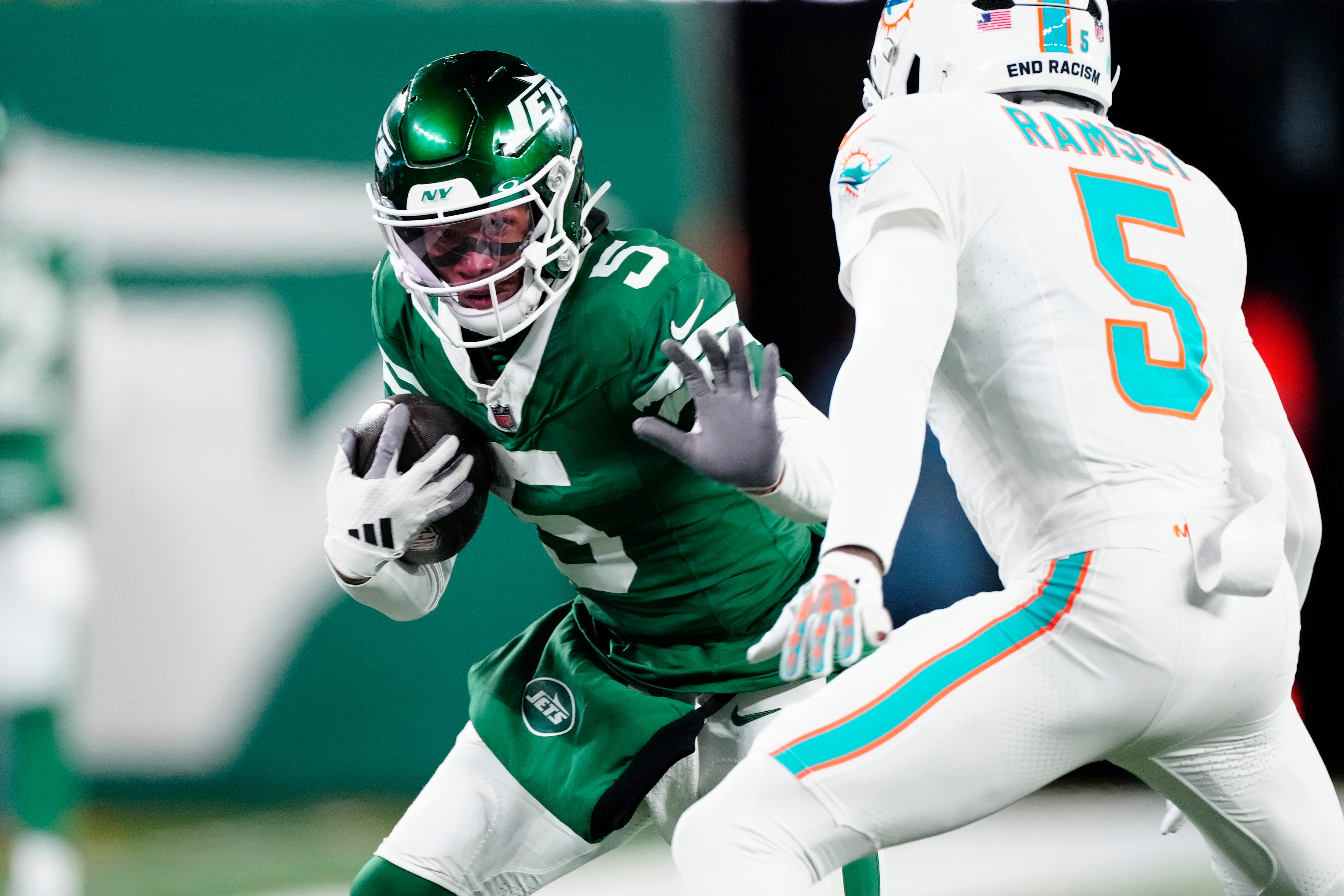 New York Jets wide receiver Garrett Wilson (5) runs with the ball as he tries to find a way past Miami Dolphins cornerback Jalen Ramsey (5), Sunday January 5, 2025, in East Rutherford.