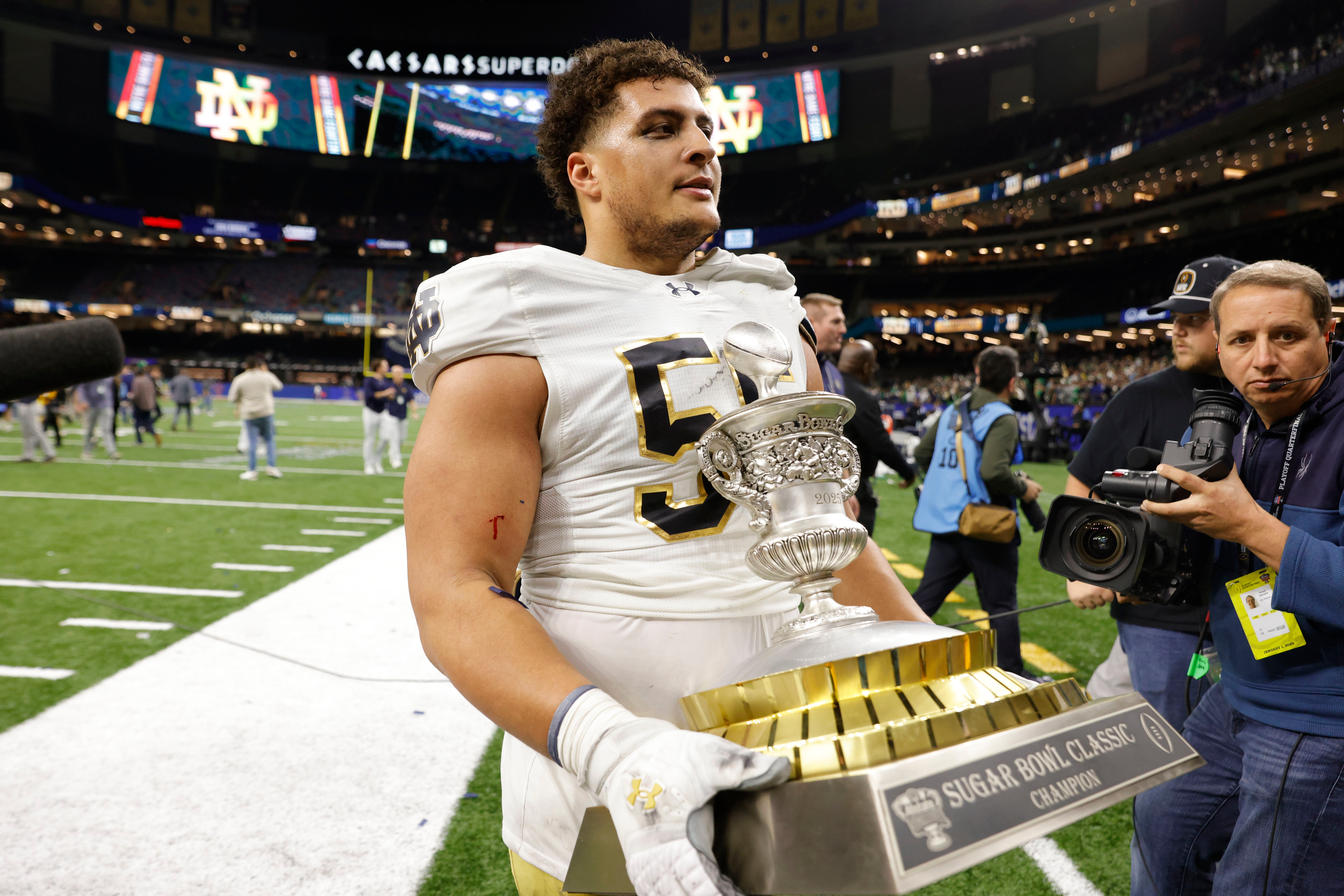 Jan 2, 2025; New Orleans, LA, USA; Notre Dame Fighting Irish defensive lineman Howard Cross III (56) carries the trophy off the field after defeating the Georgia Bulldogs at Caesars Superdome.