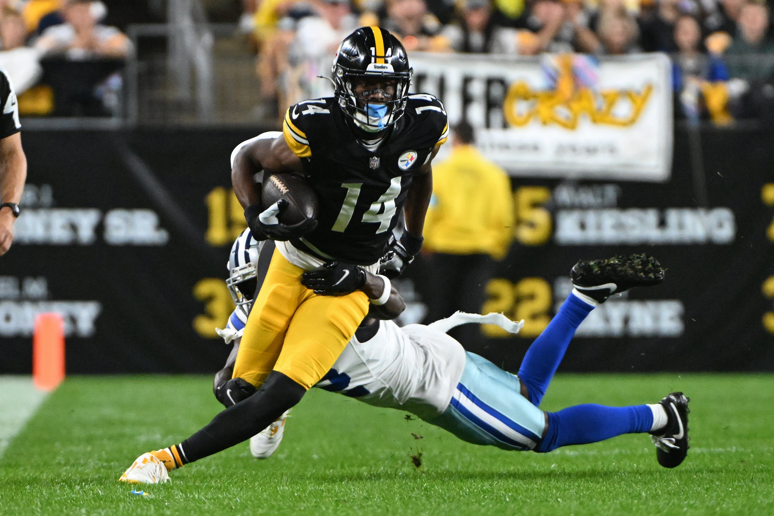 Pittsburgh Steelers wide receiver George Pickens (14) breaks a tackle by Dallas Cowboys cornerback Jourdan Lewis (2) during the first quarter at Acrisure Stadium.