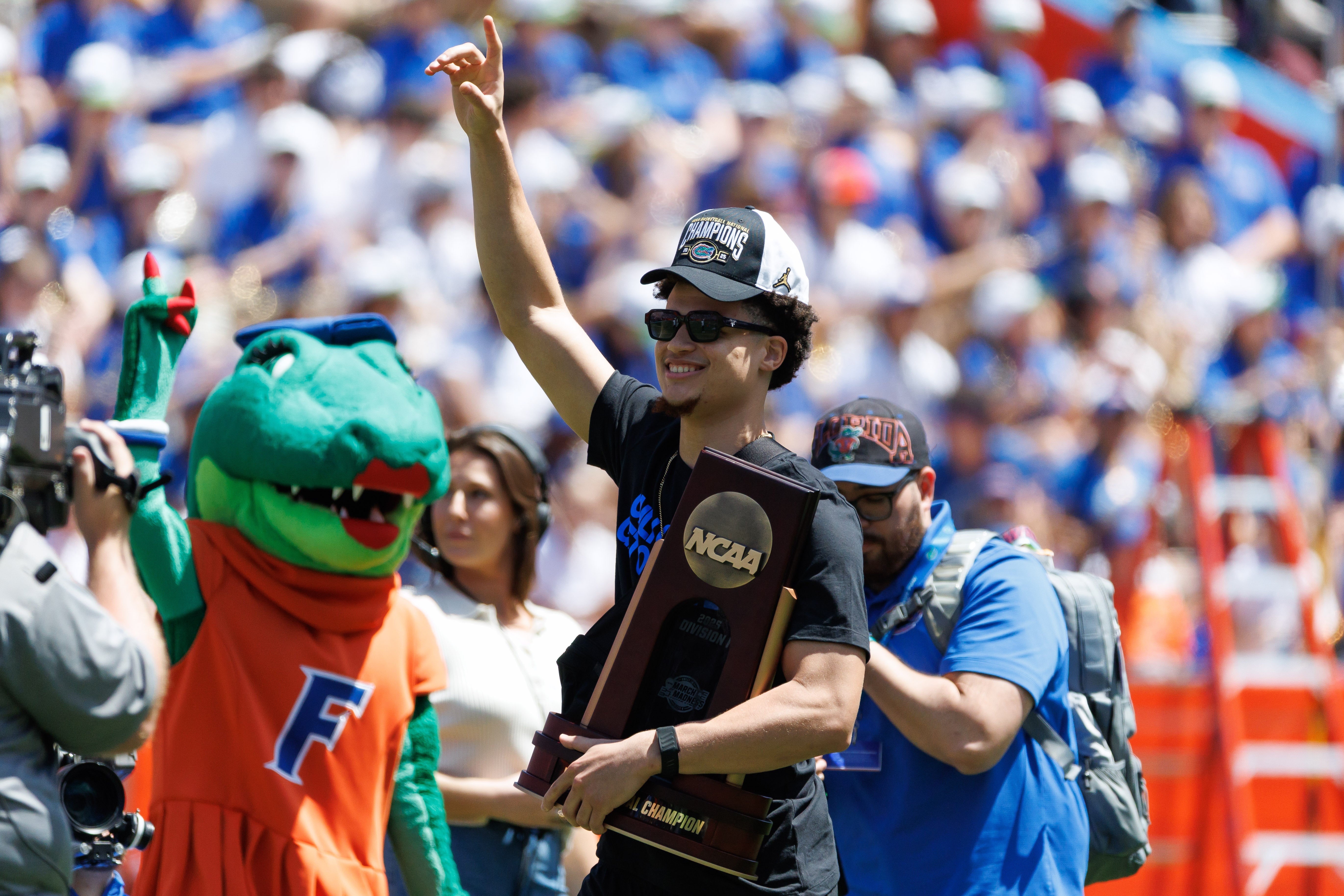 Apr 12, 2025; Gainesville, FL, USA; Florida Gators guard Walter Clayton Jr. (1) holds the National Championship trophy walking onto the field during the National Championship celebration at Ben Hill Griffin Stadium.