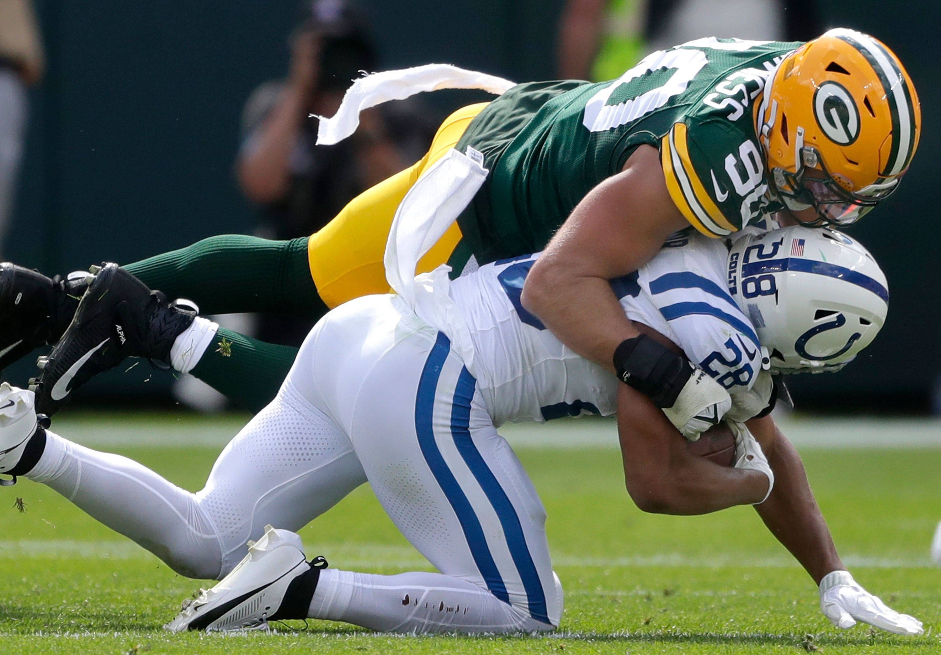 Green Bay Packers defensive end Lukas Van Ness (90) tackles Indianapolis Colts running back Jonathan Taylor (28) at Lambeau Field. 