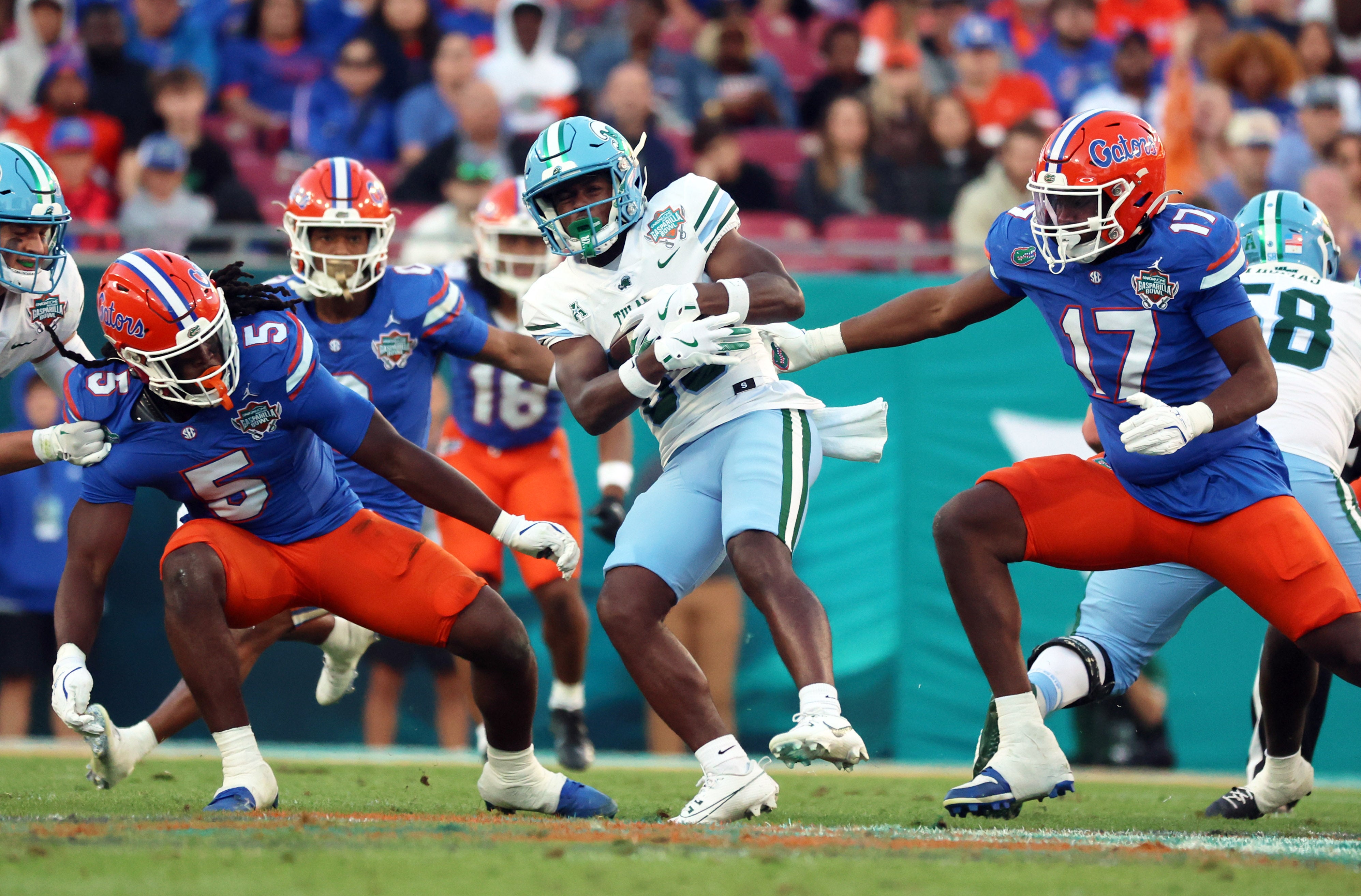 Dec 20, 2024; Tampa, FL, USA; Florida Gators linebacker Myles Graham (5) and Florida Gators edge LJ McCray (17) tackle Tulane Green Wave wide receiver Bryce Bohanon (83) during the second quarter at Raymond James Stadium.