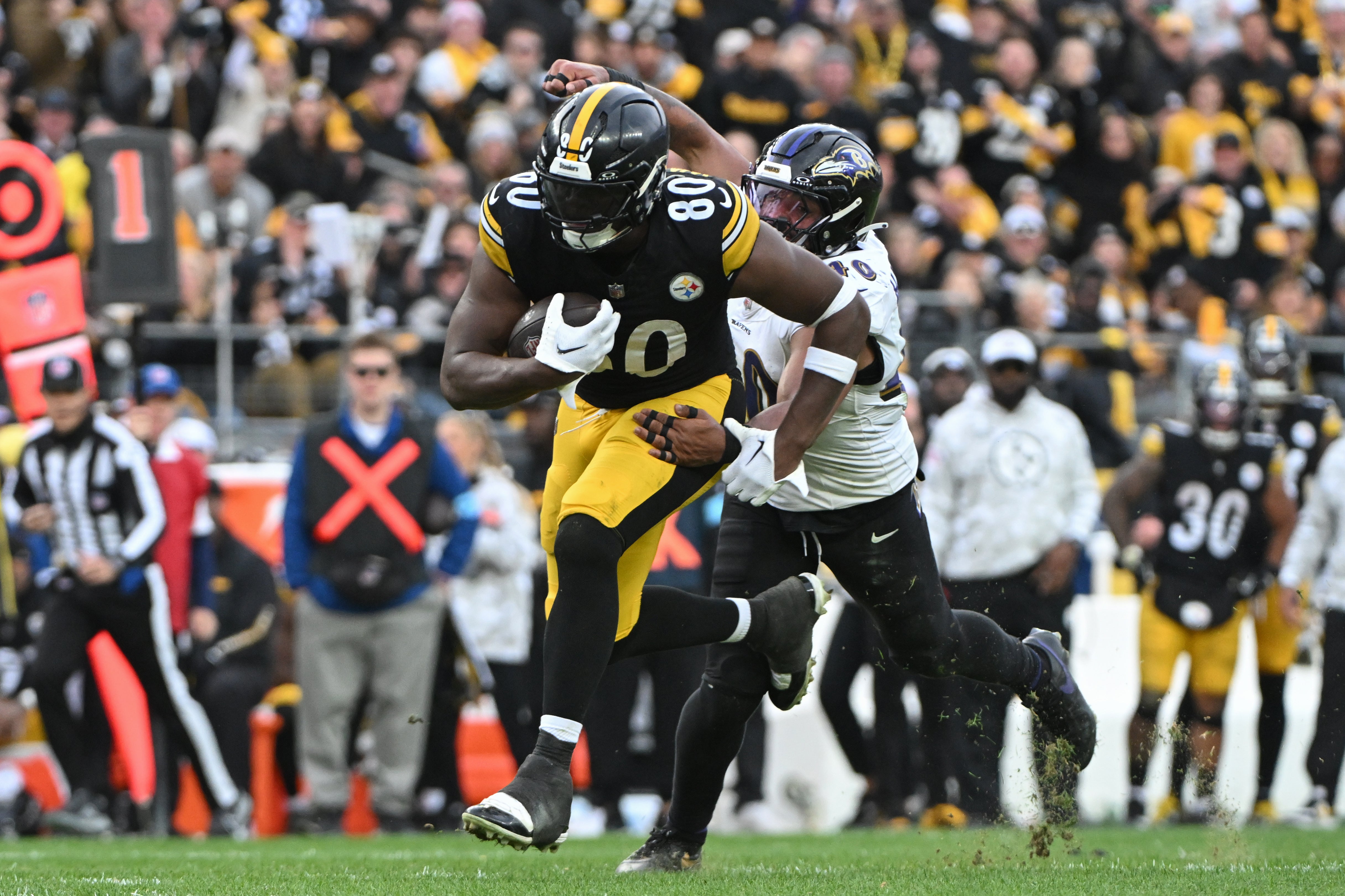 Pittsburgh Steelers tight end Darnell Washington (80) runs for extra yardage while being chased by Baltimore Ravens linebacker Malik Harrison (40) during the fourth quarter at Acrisure Stadium.
