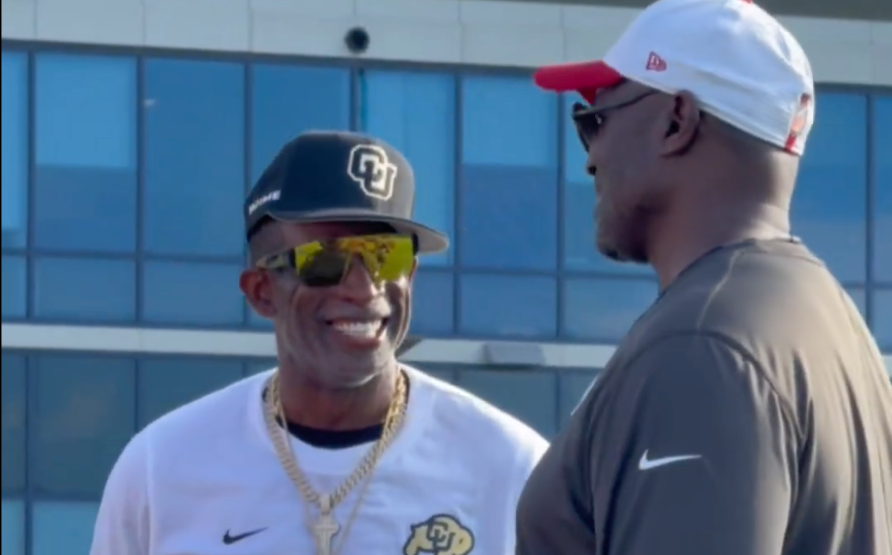 Deion Sanders speaks with Bucs head coach Todd Bowles during Day 1 of training camp.