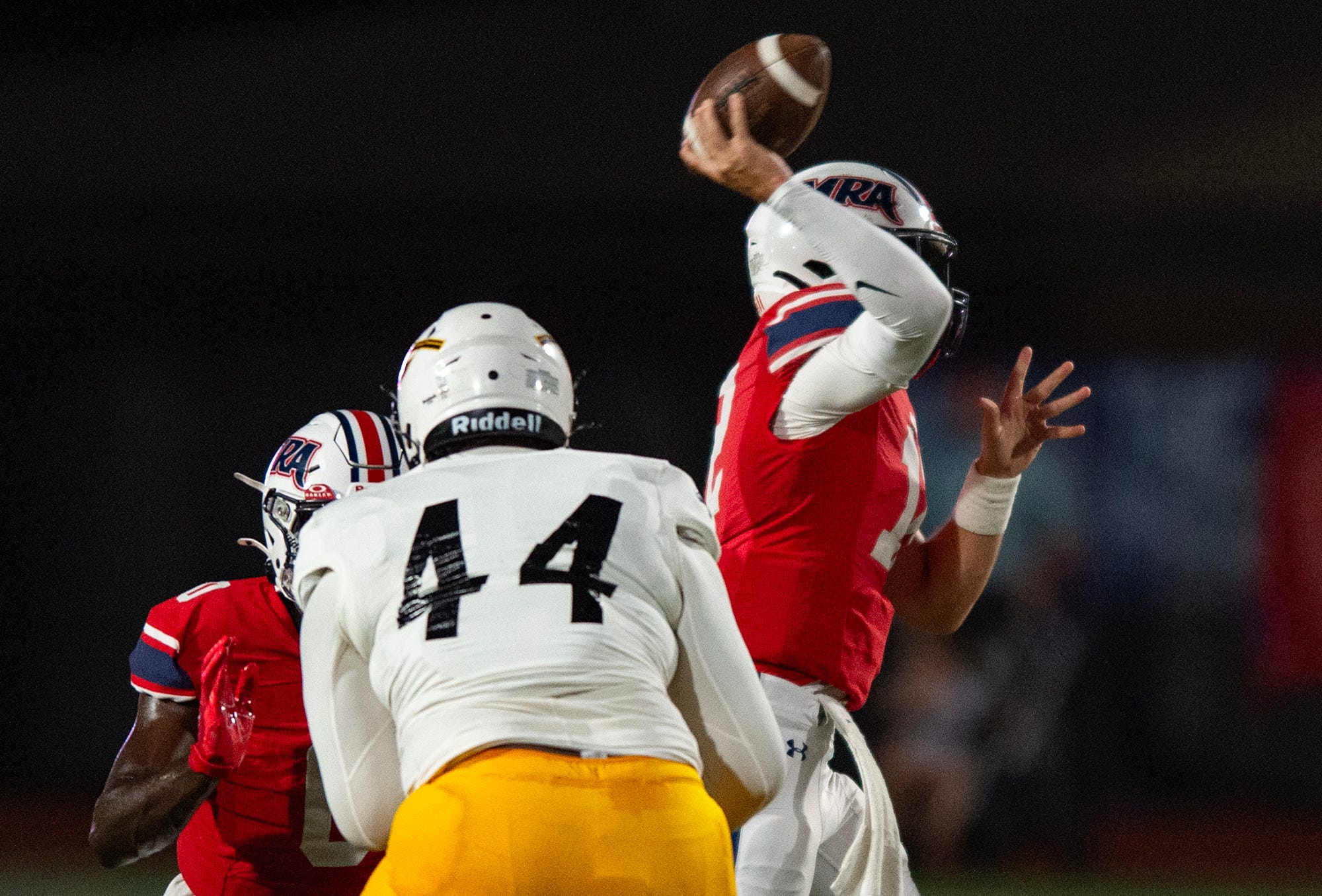 Madison-Ridgeland Academy Patriots' quarterback Samuel Stockett (12) throws the ball as Oak Grove Warriors' defensive line Deven Robertson (44) takes on MRA Patriots' running back AJ Parker (0) during the game in Madison, Miss., on Friday, Sept. 20, 2024.