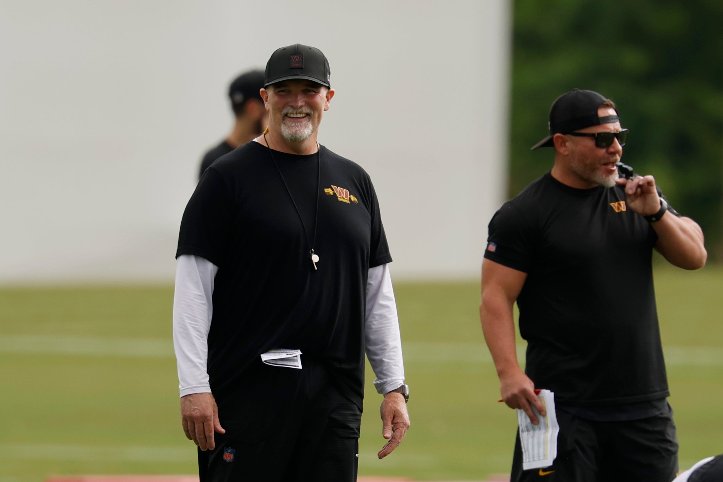Jul 23, 2025; Ashburn, VA, USA; Washington Commanders head coach Dan Quinn (M) smiles during warm up before practice on day one of training camp at OrthoVirginia Training Center at Commanders Park.