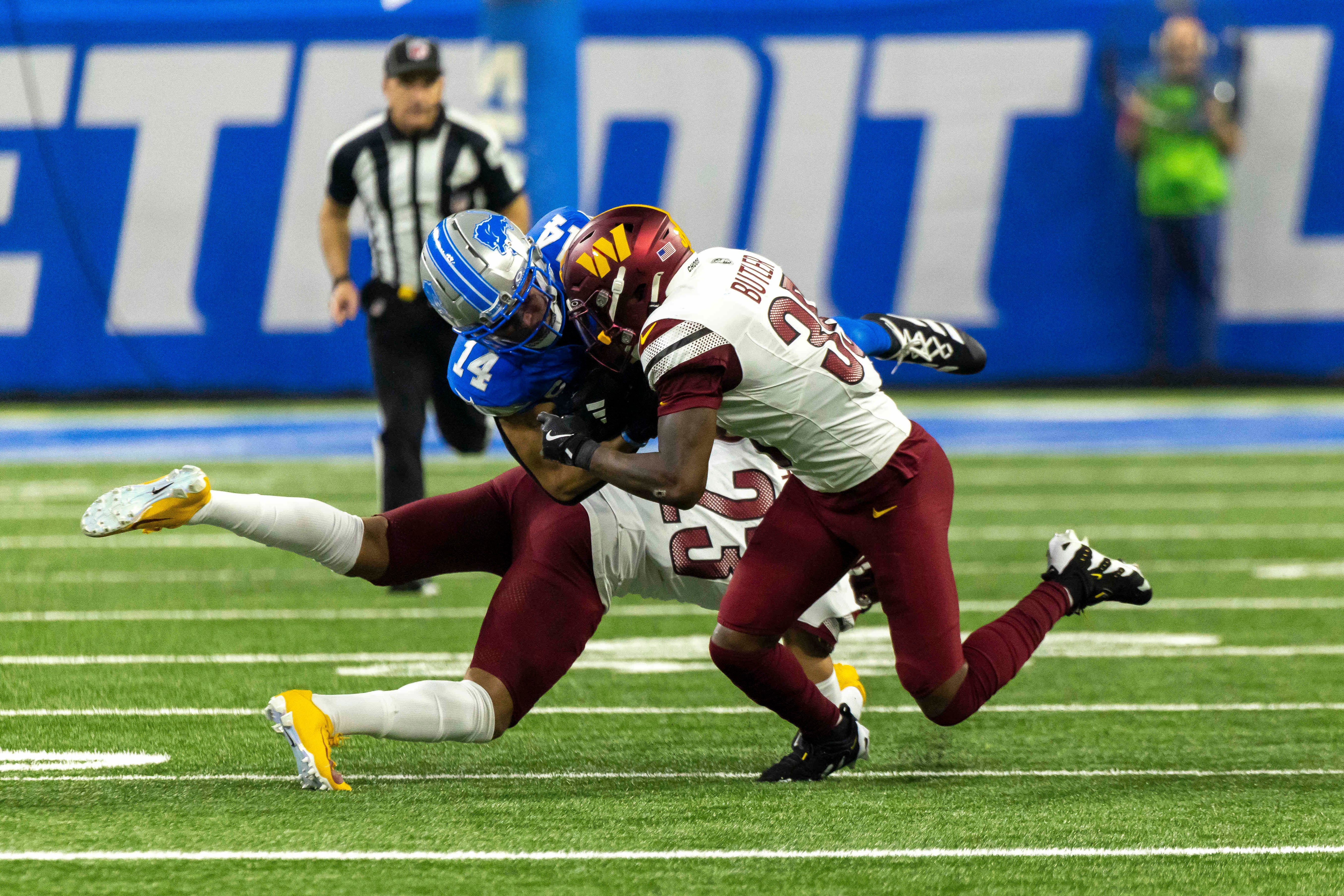 an 18, 2025; Detroit, Michigan, USA; Washington Commanders safety Percy Butler (35) and corner back Marshon Lattimore (23) tackle Detroit Lions wide receiver Amon-Ra St. Brown (14) during the second quarter at Ford Field.