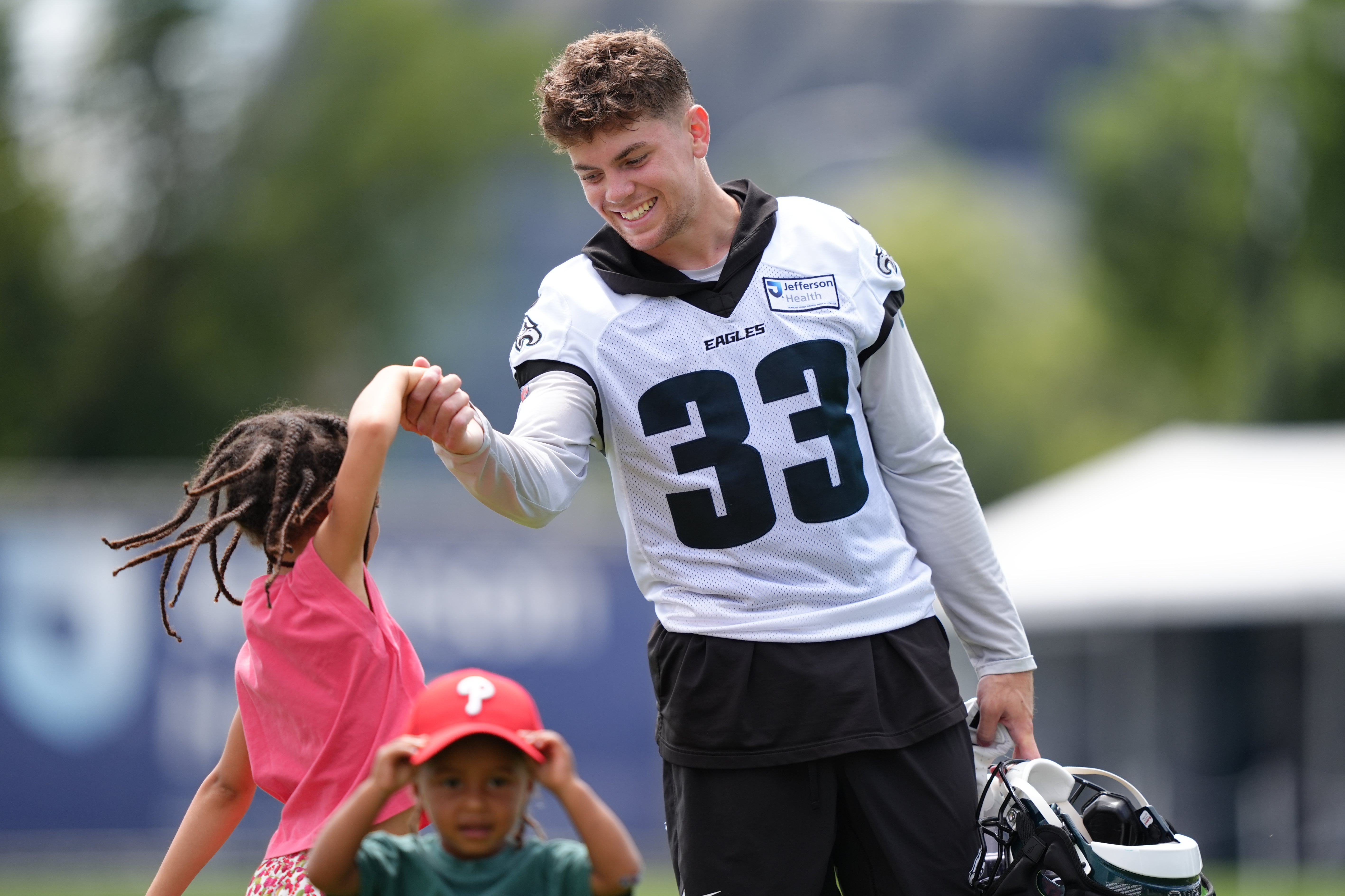 Philadelphia Eagles defensive back Cooper DeJean (33) plays with the children of running back Saquon Barkley during training camp at NovaCare Complex.